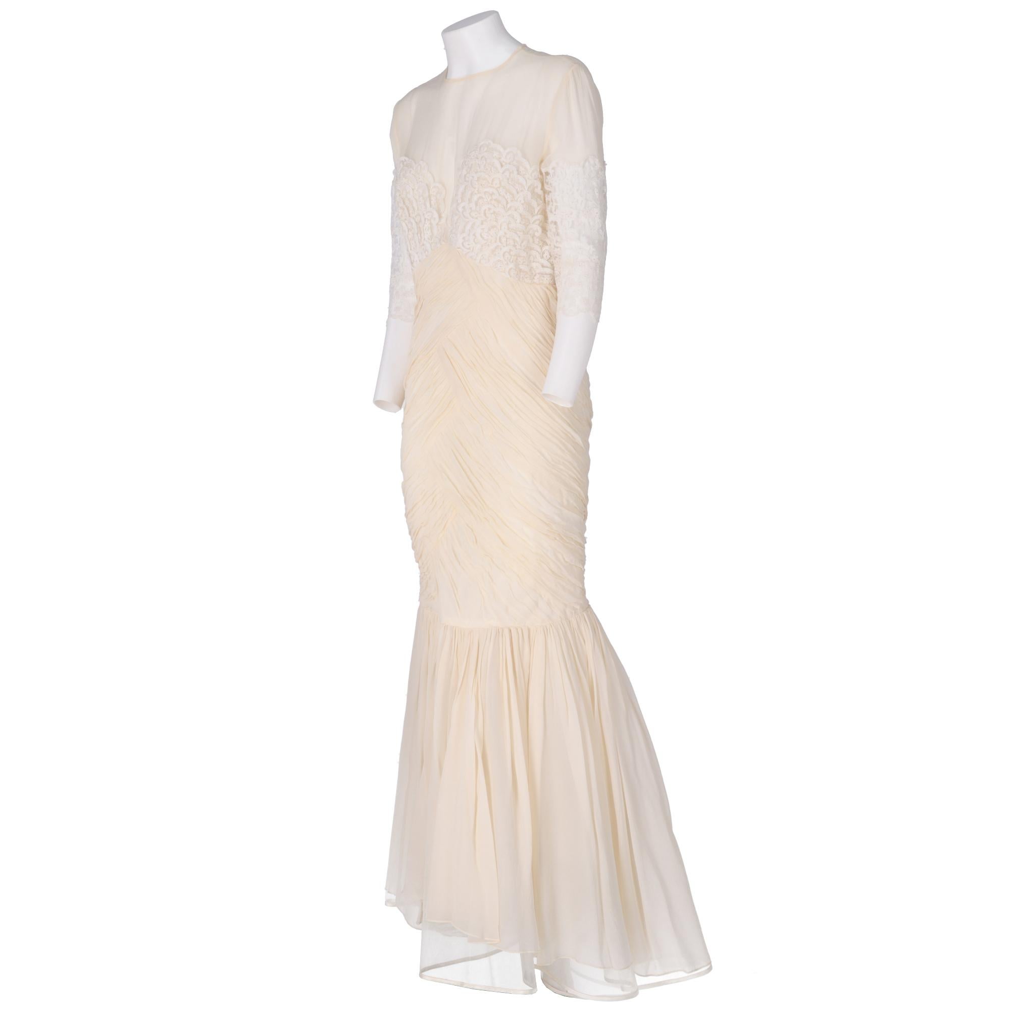 Ivory tailored wedding dress, with long gathered mermaid skirt with rigid tulle inside, crew neck, semi-transparent top with decorative white lace insert with short sleeves, zip and button closure on the back.

The dress has a tear between the