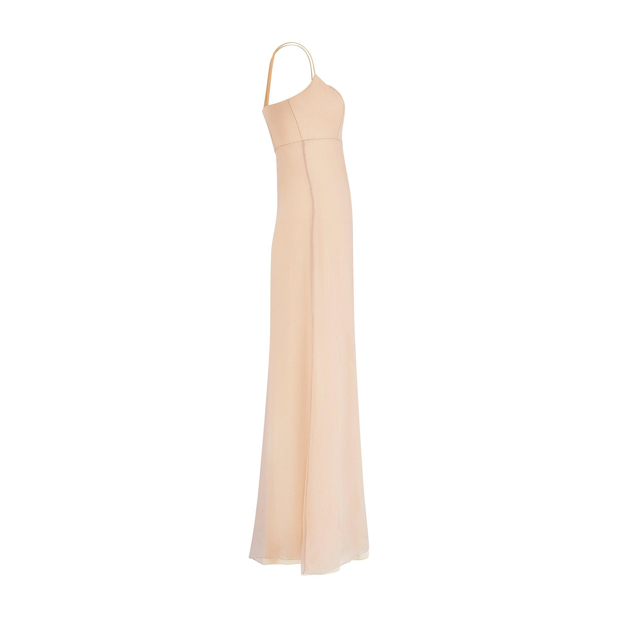 This late 1990s to early 2000s Jacques Azagury evening gown is a tailored from romantic nude silk chiffon. It is inspired by antique slip-dresses and features a structured bust which is boned at the front and back. Underneath, a sheath silhouette