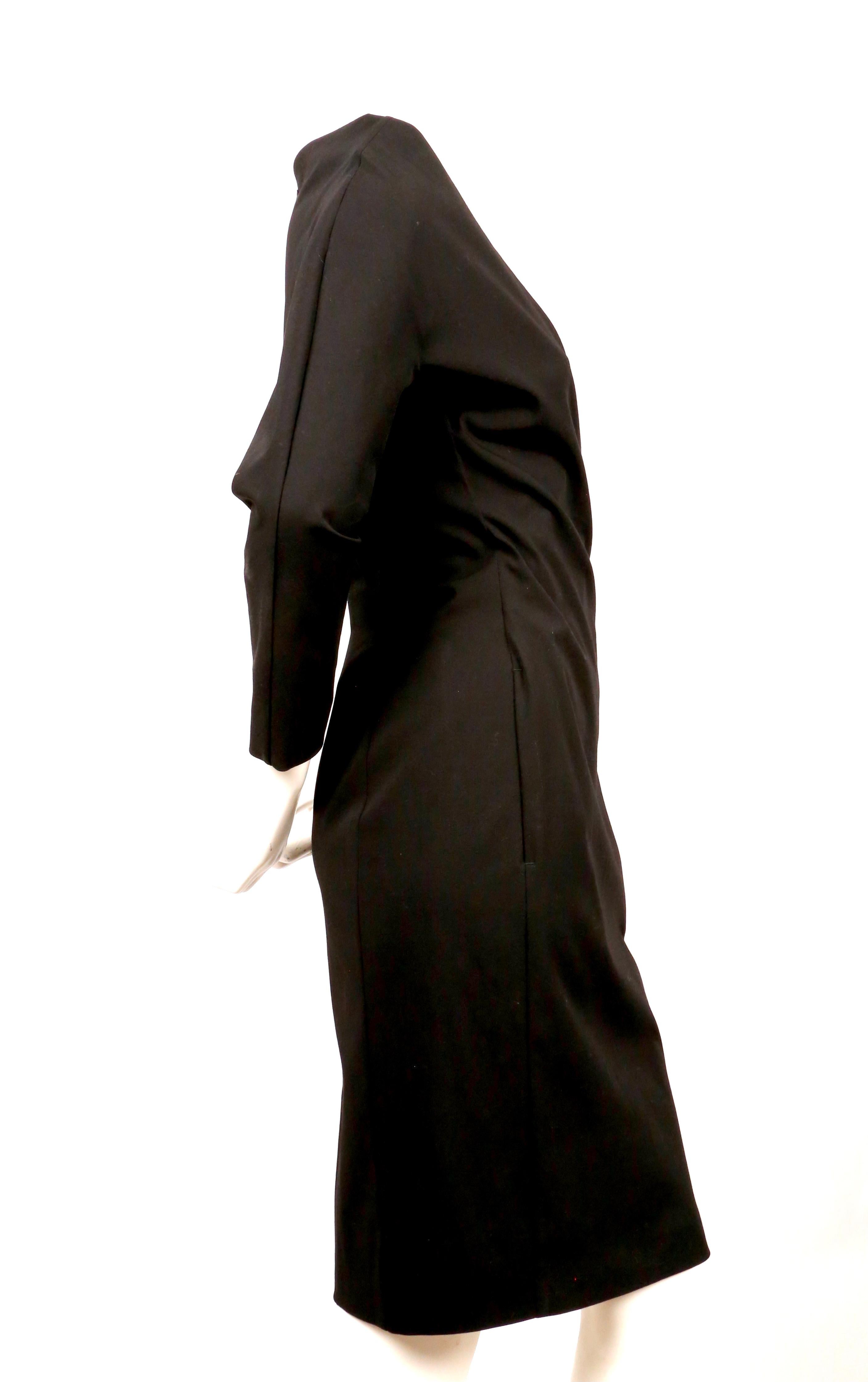 Dramatic, black wrap style dress with raised neckline designed by Jean Paul Gaultier dating to the late 1990's. Label a French size 36. Approximate measurements: bust 34