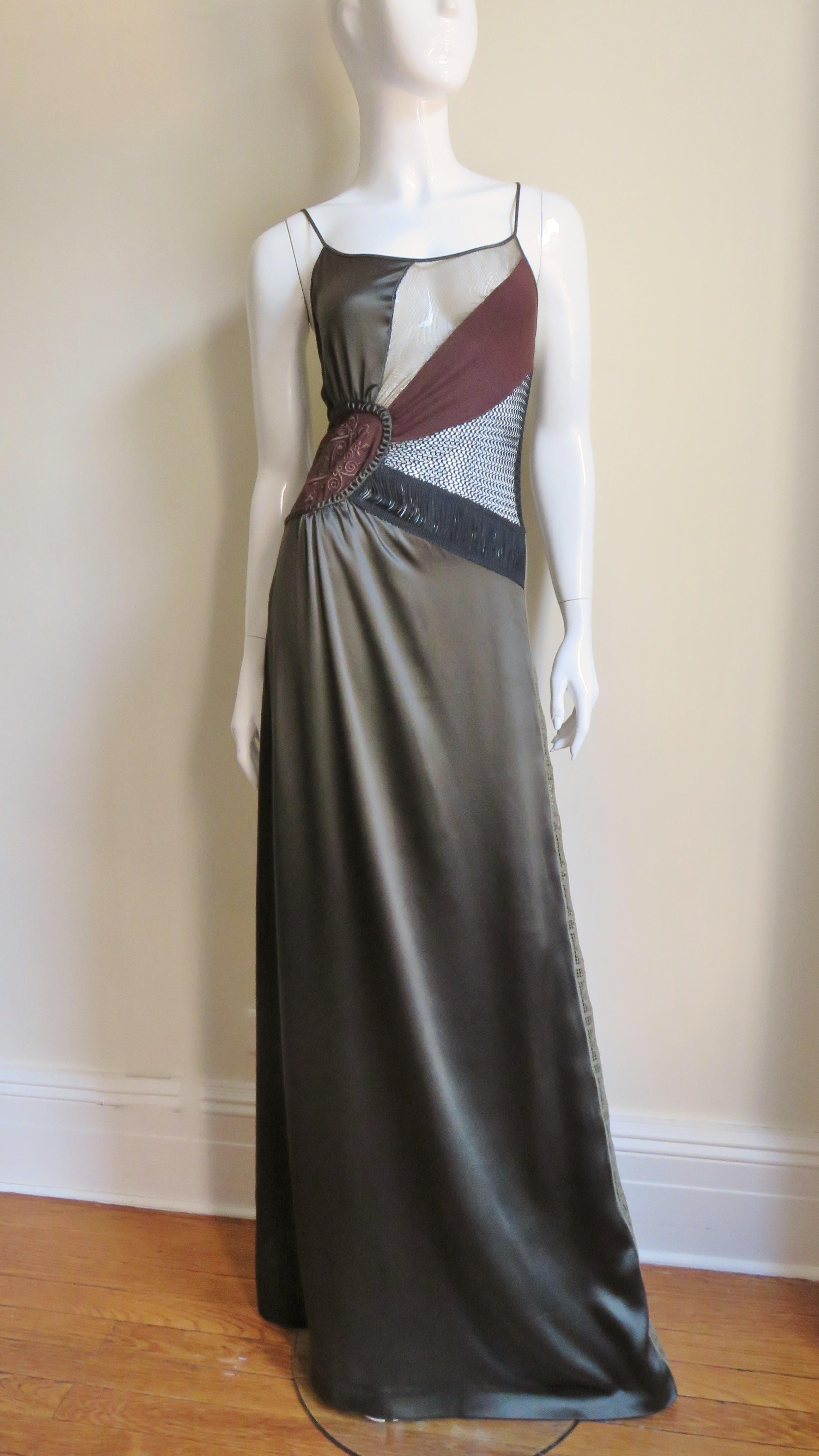 A fabulous silk slip dress from Jean Paul Gaultier in olive green.  It has spaghetti straps on a bodice highlighted at the waist with a row of black silk fringe and a detailed, richly embroidered brown crest on one side.  The bodice front is