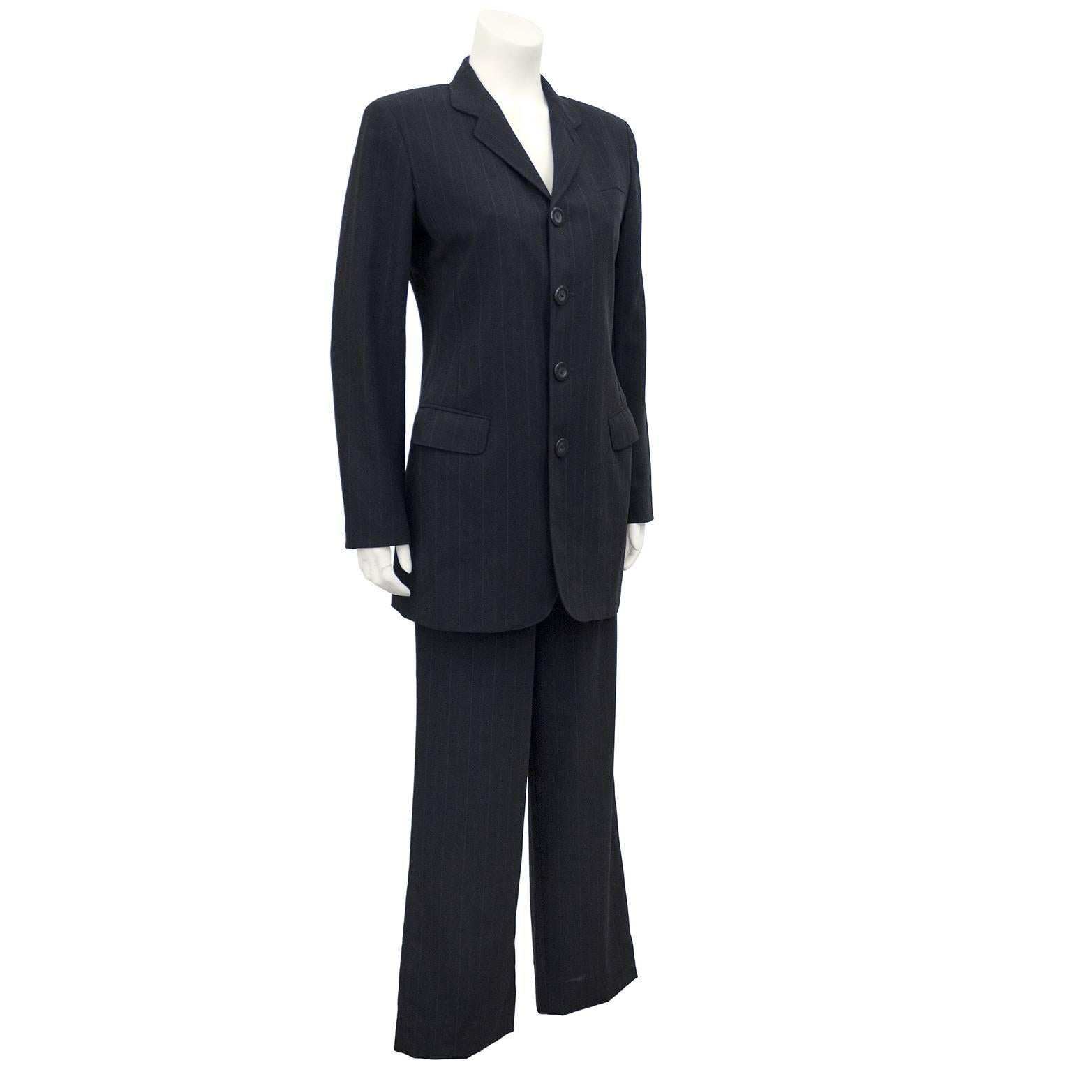 1990s Jean Paul Gaultier Femme charcoal grey wool pinstripe pantsuit. Long single breasted riding style jacket with large, round plastic buttons. One slit pocket at bust and two patch flap pockets at hips. High waisted, flat front trousers with a