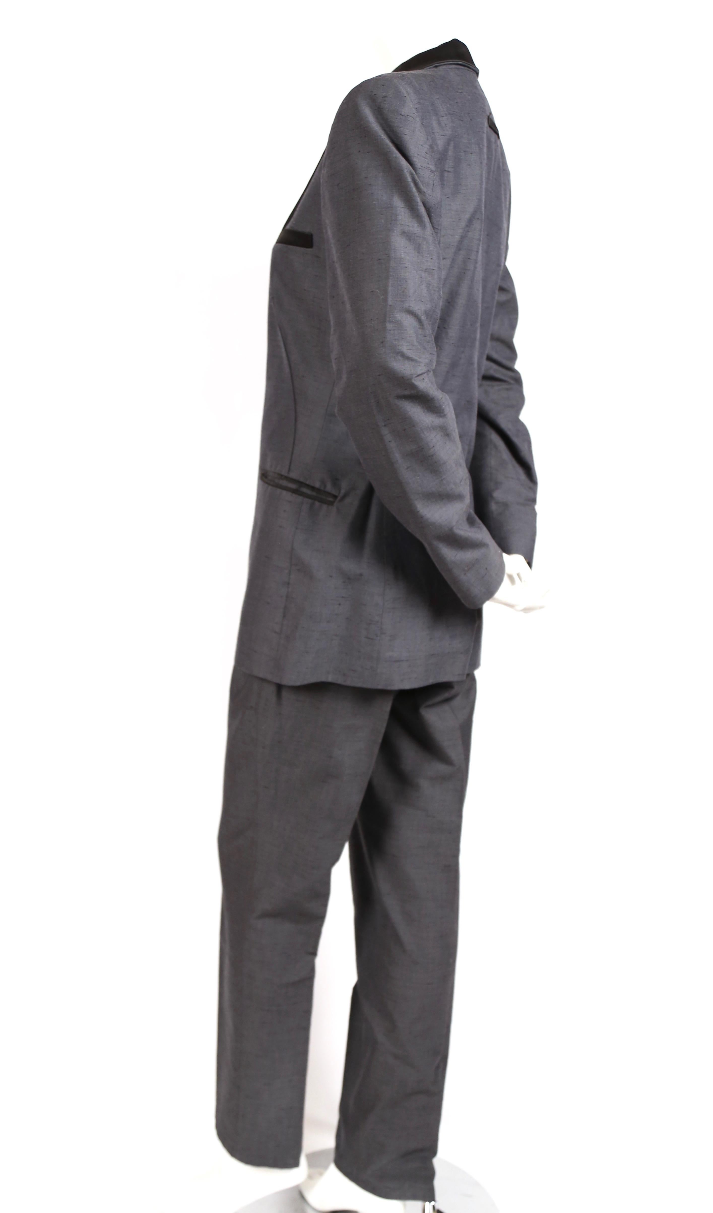 Dark grey suit with black trim and silver safety pin and chain detail designed by Jean Paul Gaultier dating to the 1990's. French size 40/ Italian size 44. Approximate measurements for jacket: shoulders 16