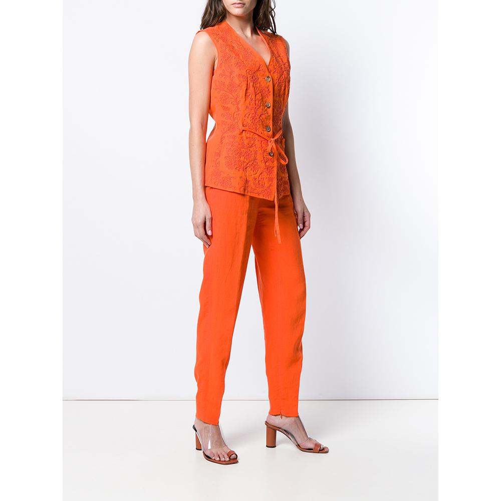 Jil Sander trousers, vest and top set in orange linen, with straight trousers, front closure with button and zip, welt pockets; waistcoat with embroidered details, front closure with buttons and belt; short top with back closure with knot.

Years: