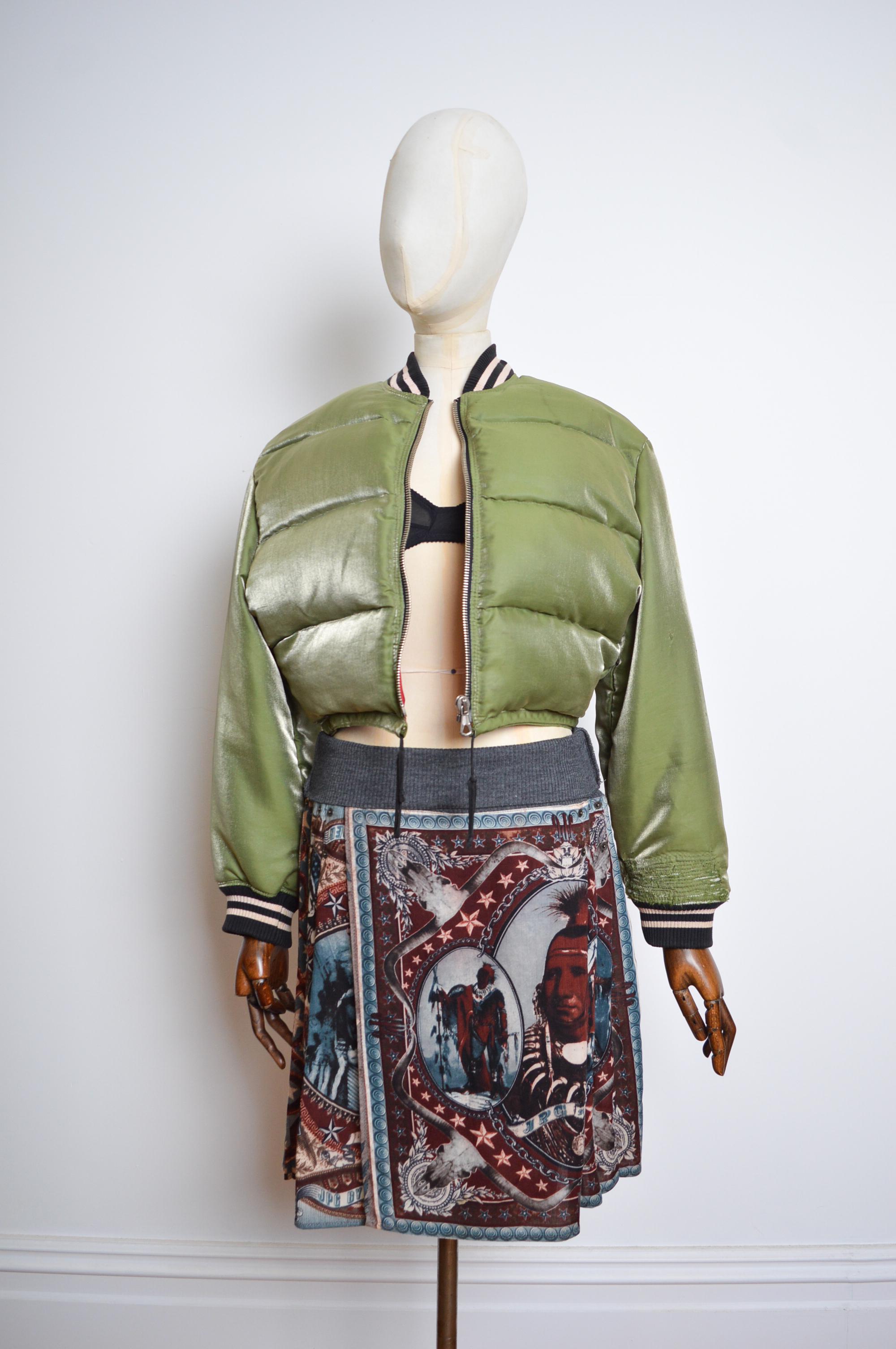 Superb 1990's Vintage Cropped MA1 style military, Khaki green bomber jacket by Jean Paul Gaultier, with a Detachable hood bonnet detail.

Features;
Contrast knitted jersey cuffs & Collar
Red acetate interior lining
Draw tie waist line
Central line