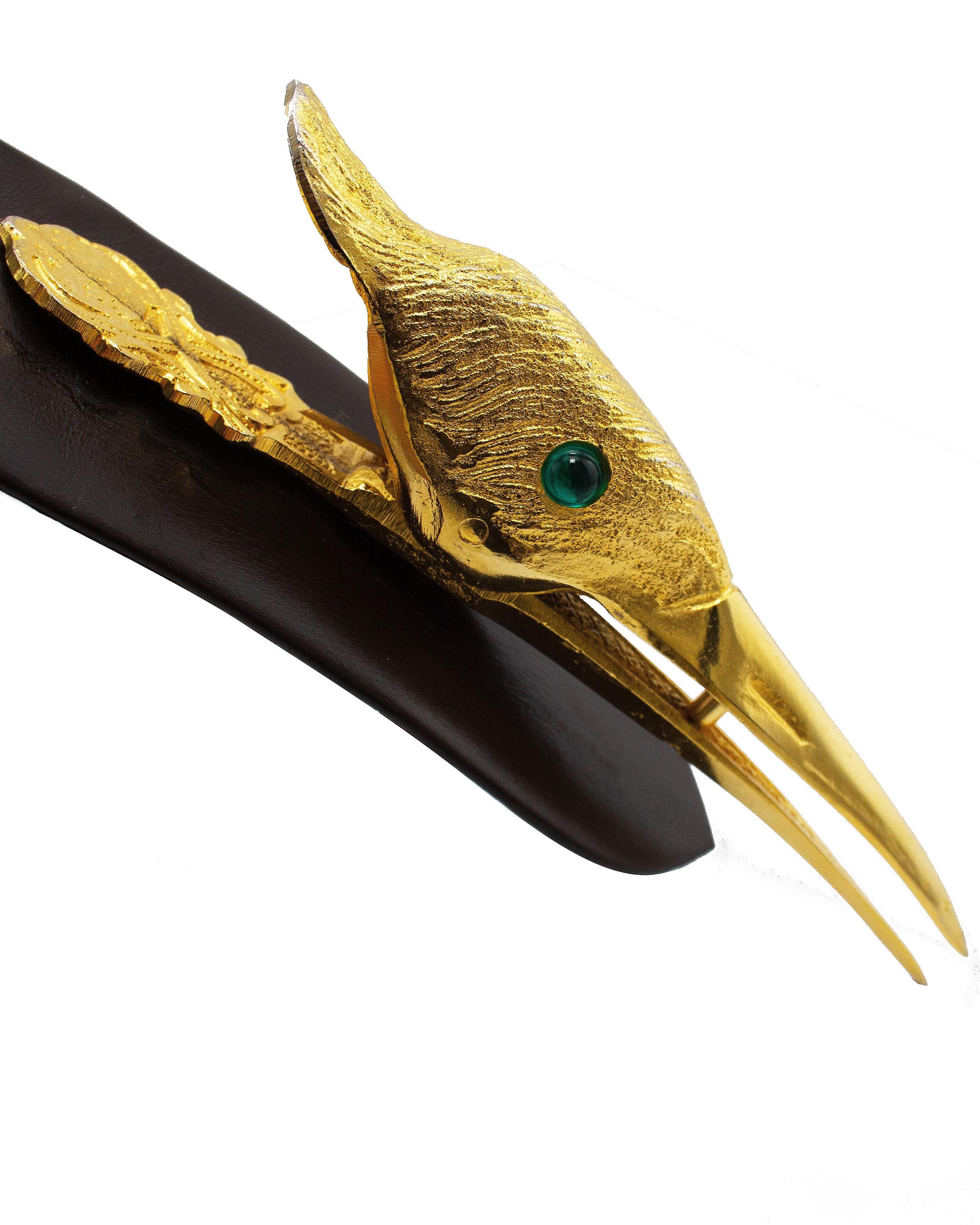Very interesting and unique Judith Leiber statement belt from the early 1990s. Chocolate brown supple leather with a very large gold tone metal bird head buckle. The bird features an engraved head to give the illusion of feathers and faux emerald