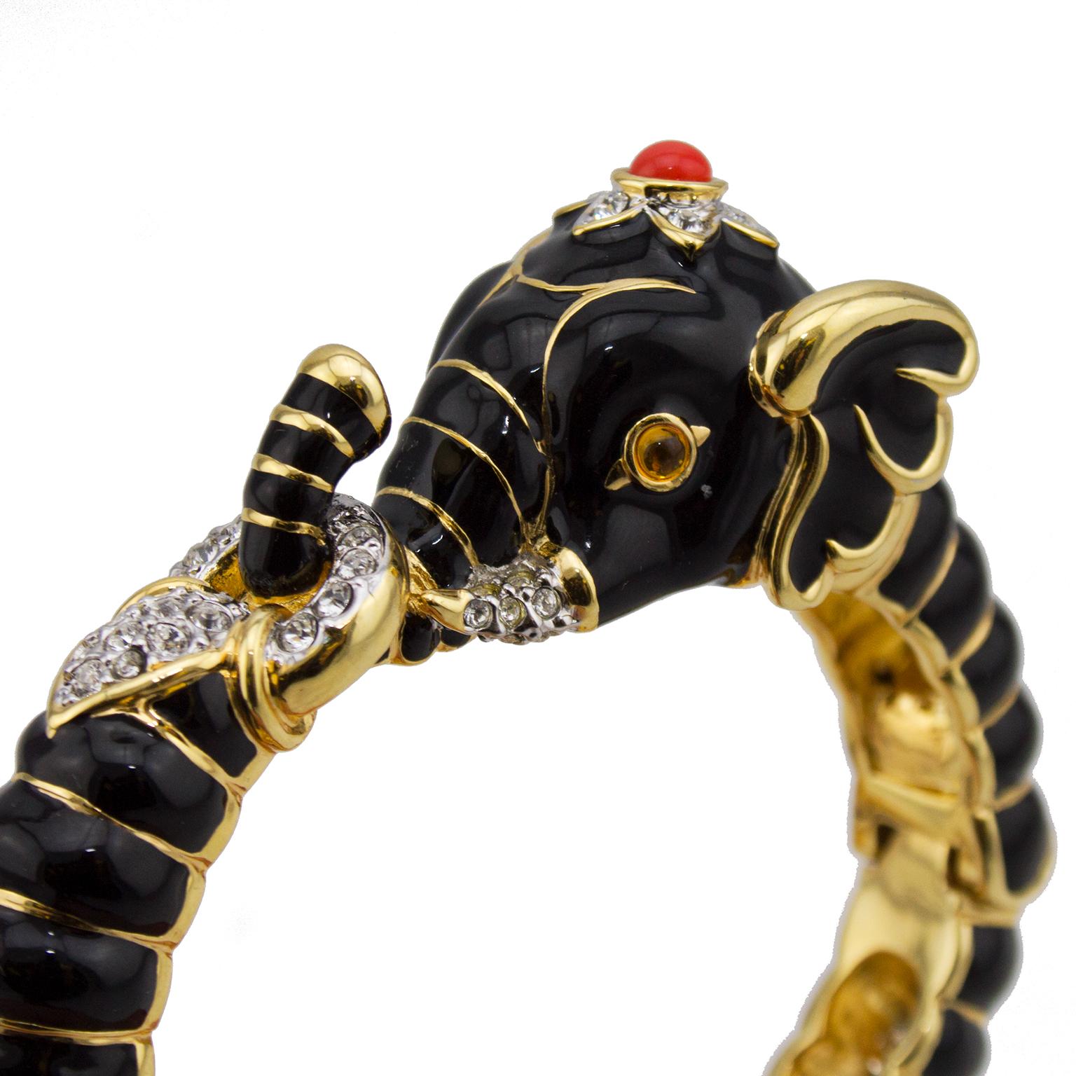 Gorgeous KJL black enamel and gold elephant shaped clamper bracelet with rhinestone and orange cabochon accent. This bracelet was produced in at least 6 different colors between the 1980s and the 1990s. The elephant features it's trunk hooked