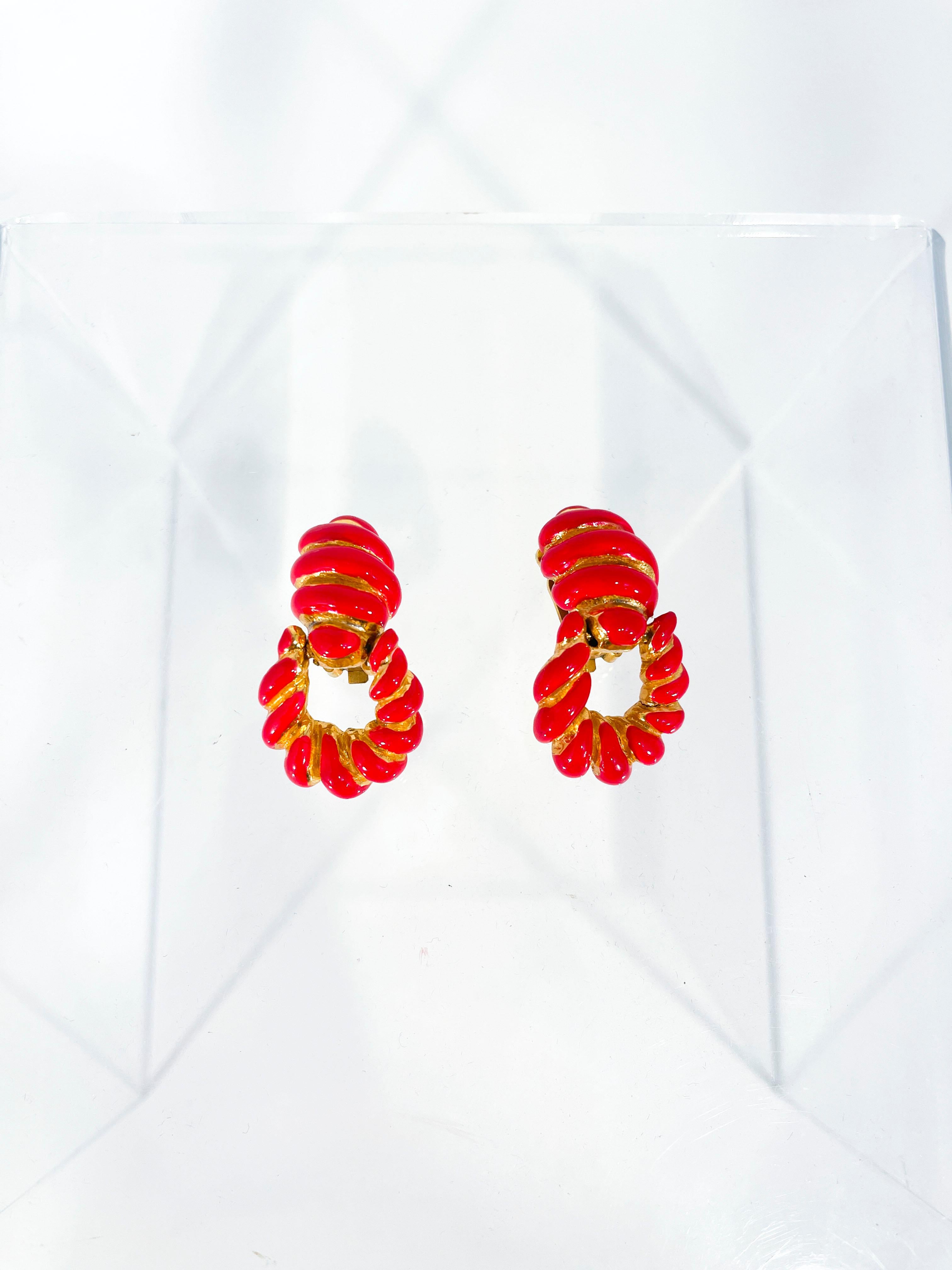 1990's Kenneth Jay Lane clip-on earrings. These clip-on earrings are gold toned featuring fire engine red enamel in a Door Knocker motif. The rounded articulated 