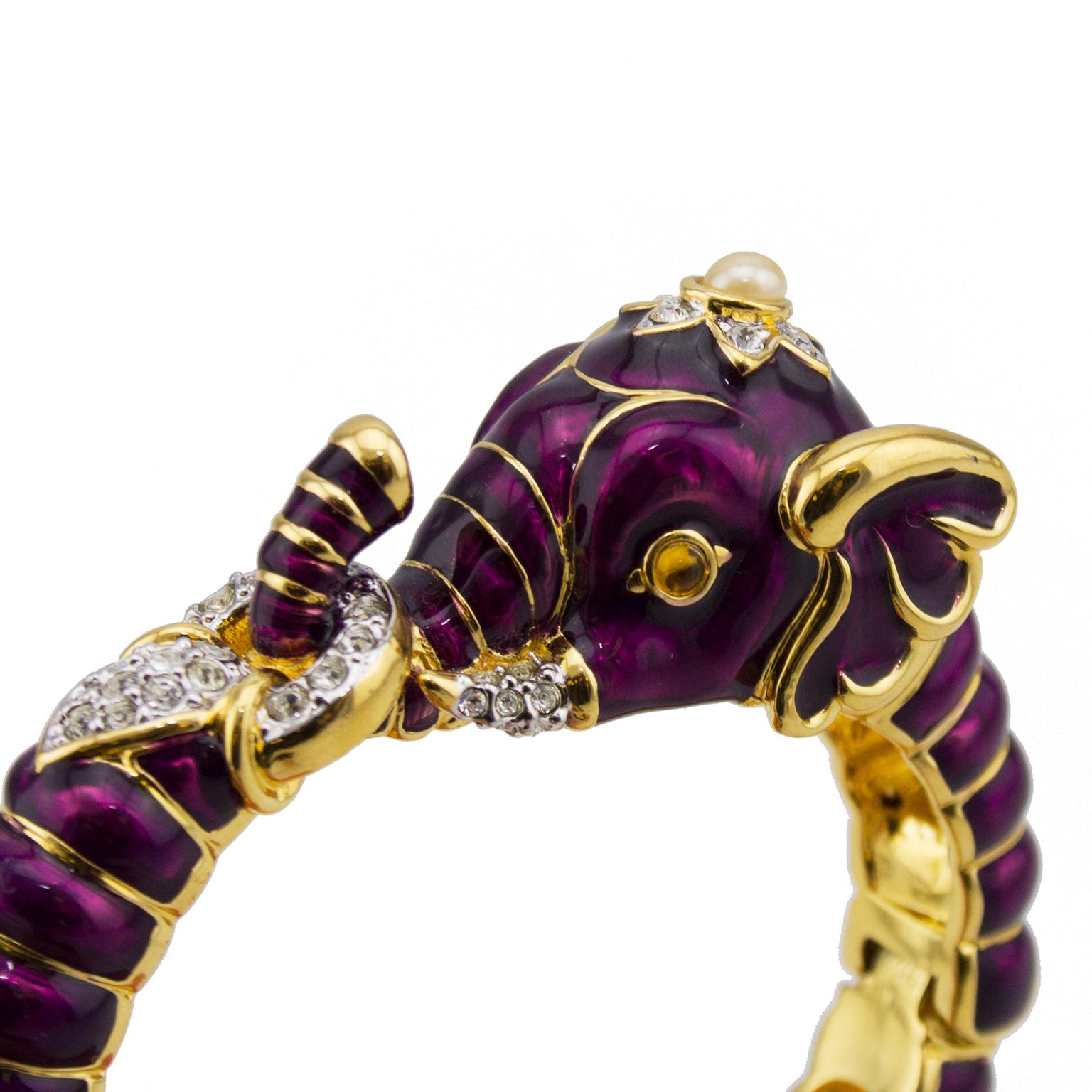 Gorgeous KJL purple enamel and gold elephant shaped clamper bracelet with rhinestone and pearl accent. This bracelet was produced in at least 6 different colors between the 1980s and the 1990s. The elephant features it's trunk hooked upwards through