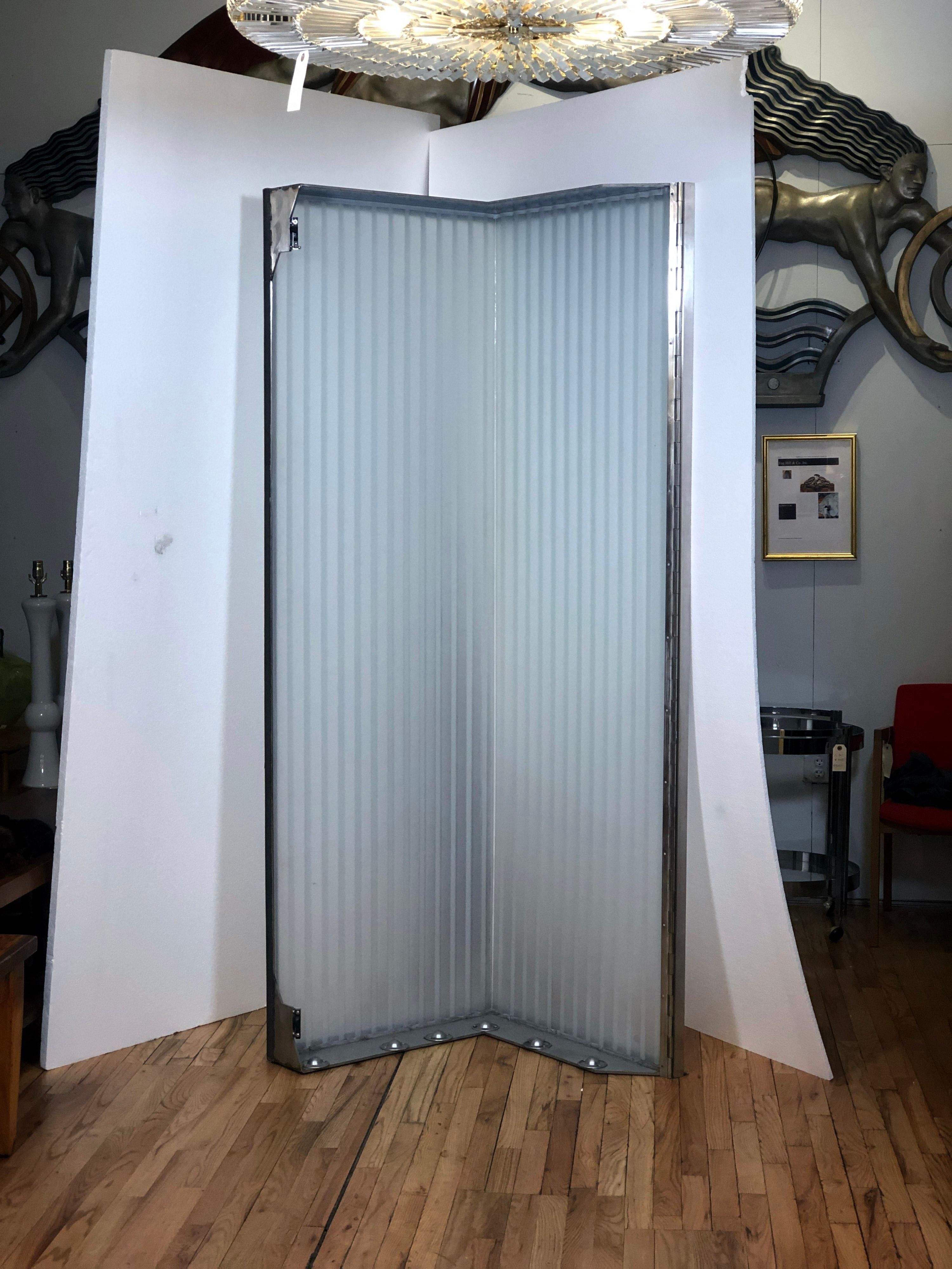 This is part of a 32 foot high lobby light fixture from 1991 in midtown Manhattan. Each unit consists of a large 90 degree brushed stainless steel frame enclosing a translucent corrugated glass piece Each unit sits on ball bearing wheels for easy