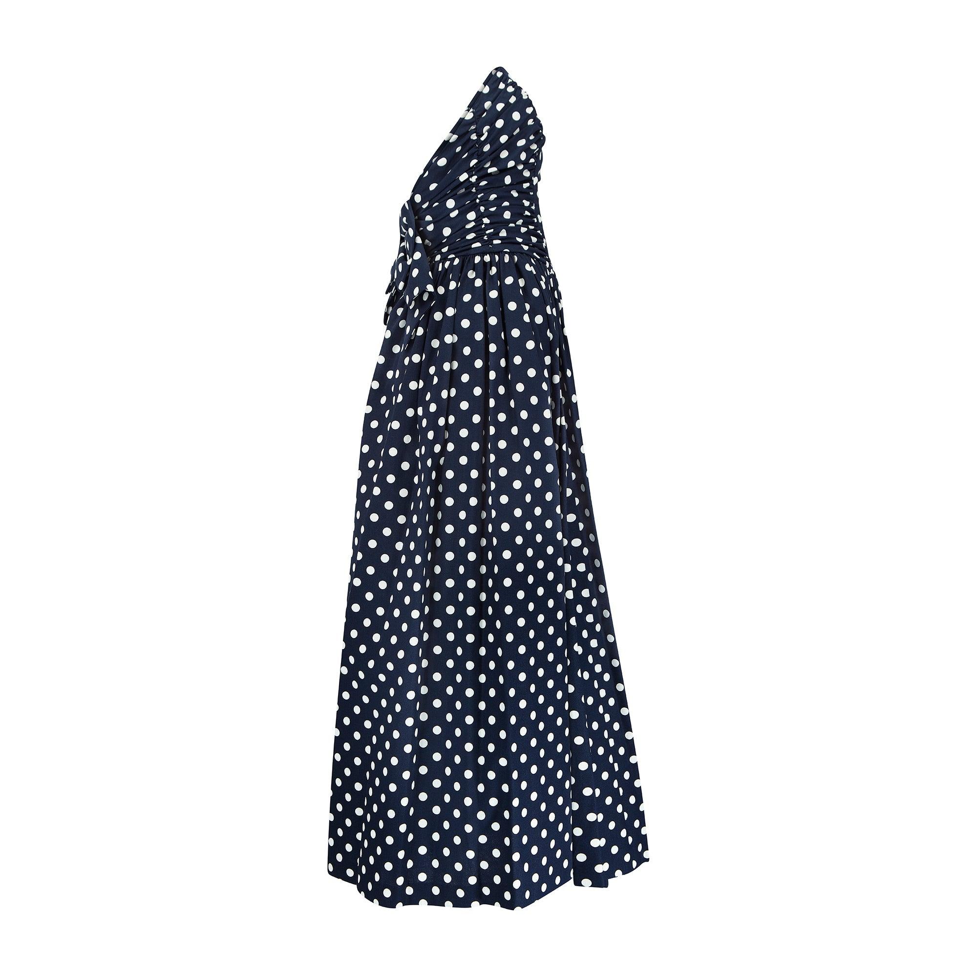 Este alegre vestido de lunares es obra del icono de la ropa de día de finales del siglo XX, Laura Ashley. Confeccionado en algodón azul marino de calidad y peso medio, con estampado integral de lunares blancos, está cortado con falda y cintura