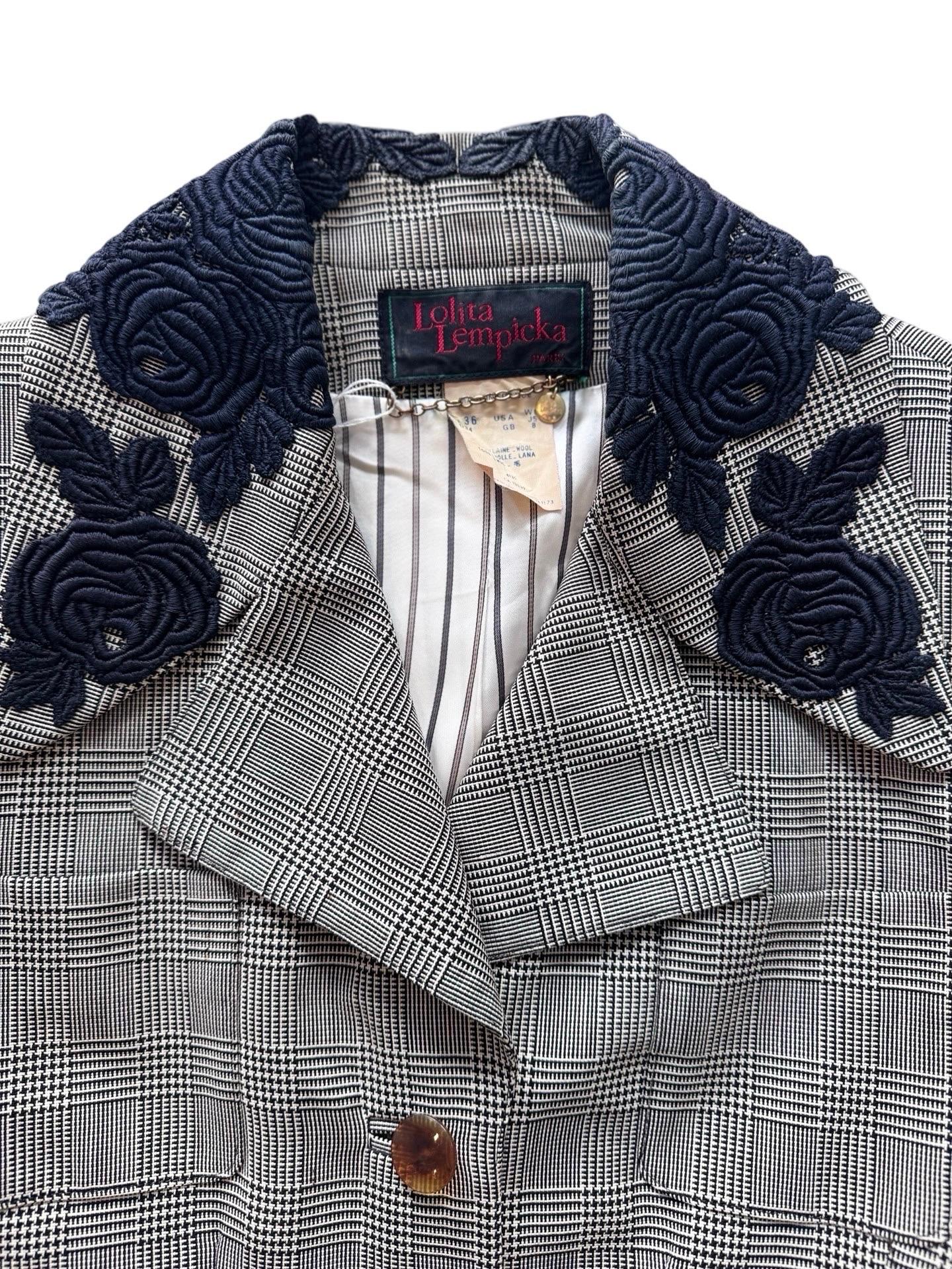 Dieser Rockanzug ist genau der romantische französische Stil, für den Lolita Lempicka bekannt ist.  Einfarbiger, leichter Wollstoff mit Hahnentrittmuster und schwerer Rosenapplikation am Kragen.  Es ist ein kurzer, taillierter Blazer mit