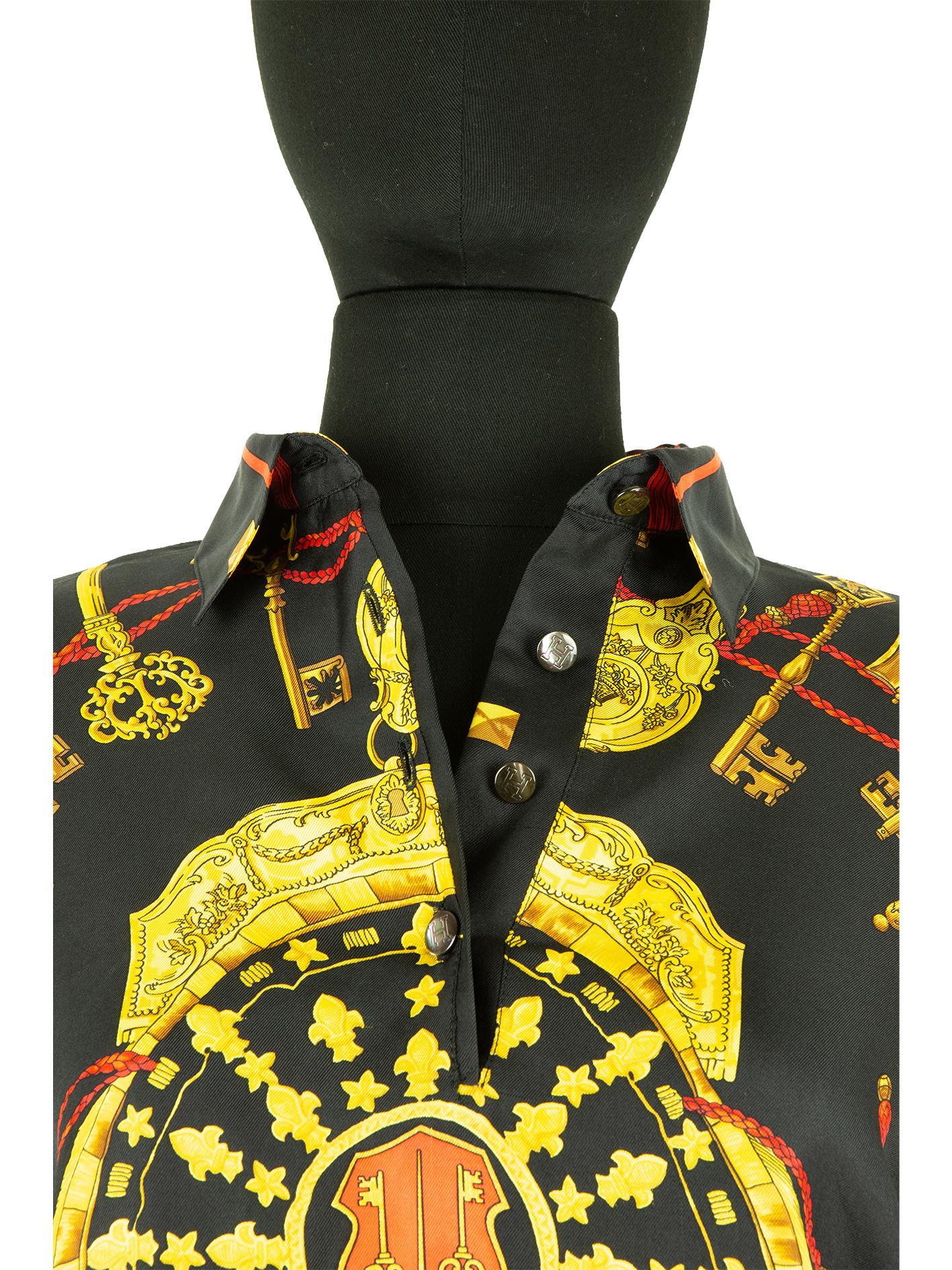 A 1990s Hermès long sleeve top with baroque style print on silk featuring a selection of gold-coloured keys laid on a red braided cord all of which circle the gold shield in the centre. This style of print is synonymous with Hermès’ designs and