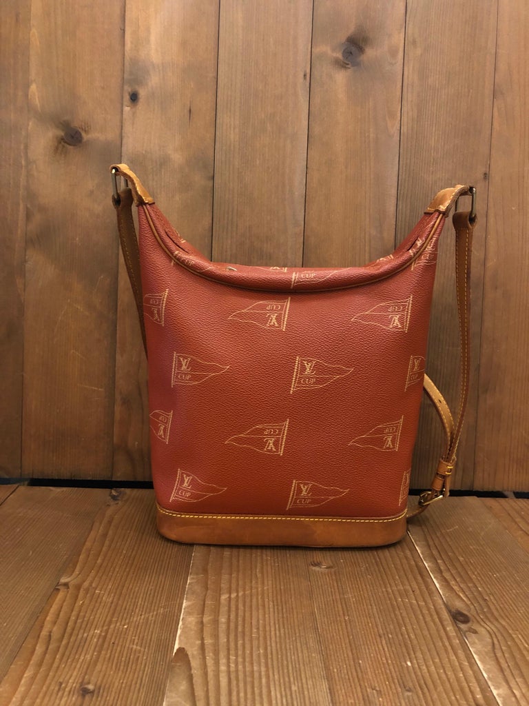 1990s LOUIS VUITTON LV Cup crossbody bag in red America’s Cup coated canvas and cowhide leather featuring one interior open pocket. Made in France with date-code MI1914. Measures approximately 11 x 8.5 x 4 inches Strap drop 18 inches.

Condition: