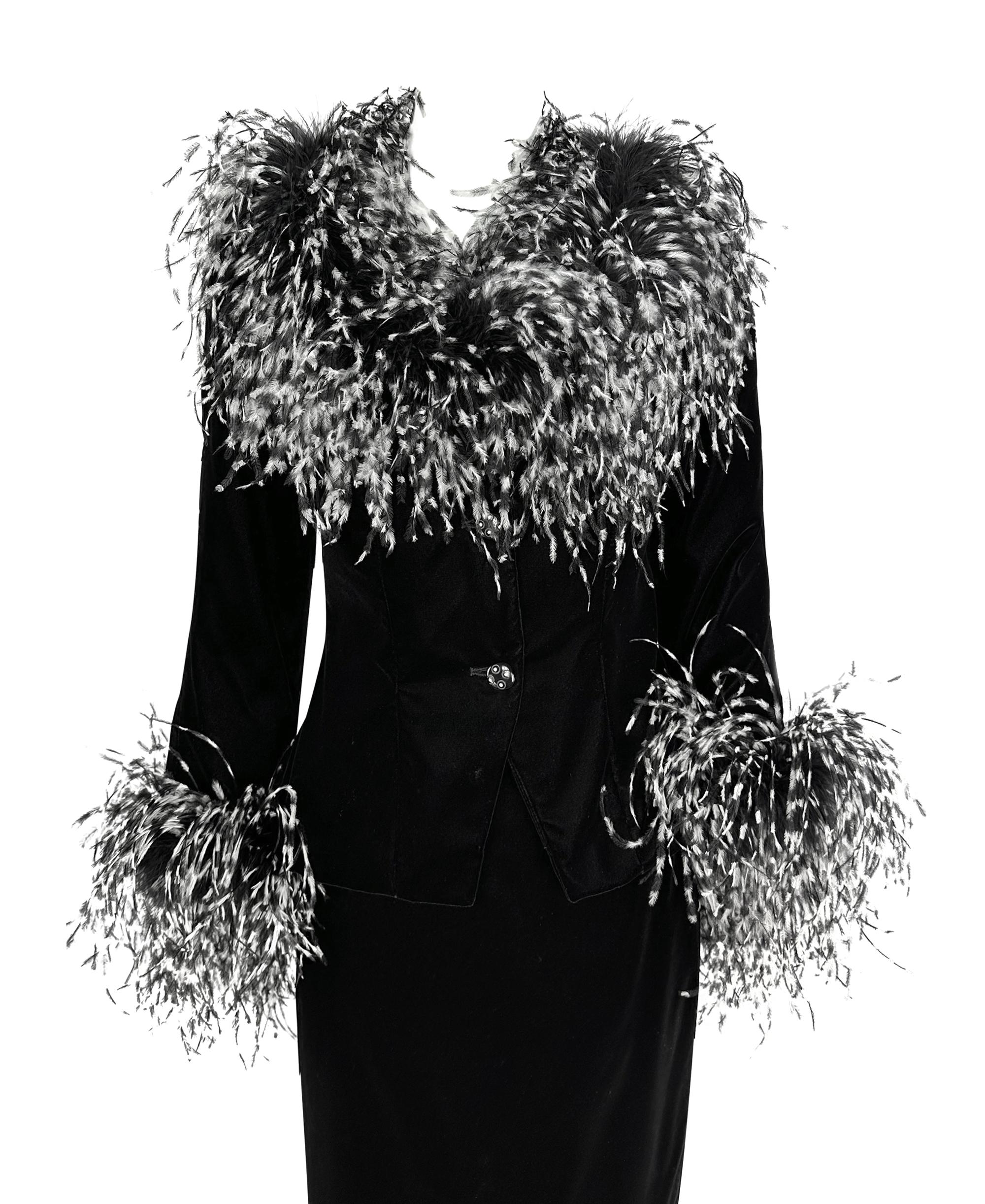 This 1990s Bob Mackie set includes a luxurious black velvet jacket, matching maxi skirt, and handbag, adorned with black and white ostrich feathers. The jacket features a dramatic feather-trimmed collar and cuffs, adding bold glamour to the tailored