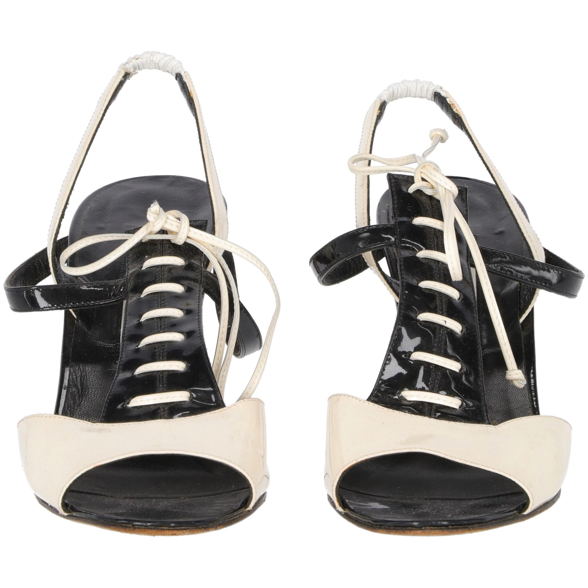 Sophisticated Manolo Blahnik bicolor ivory and black patent leather slingback sandals with an elasticated insert in optical white real leather. These bontone style shoes features a black patent leather detail, faux leather lace-up and bow. Black