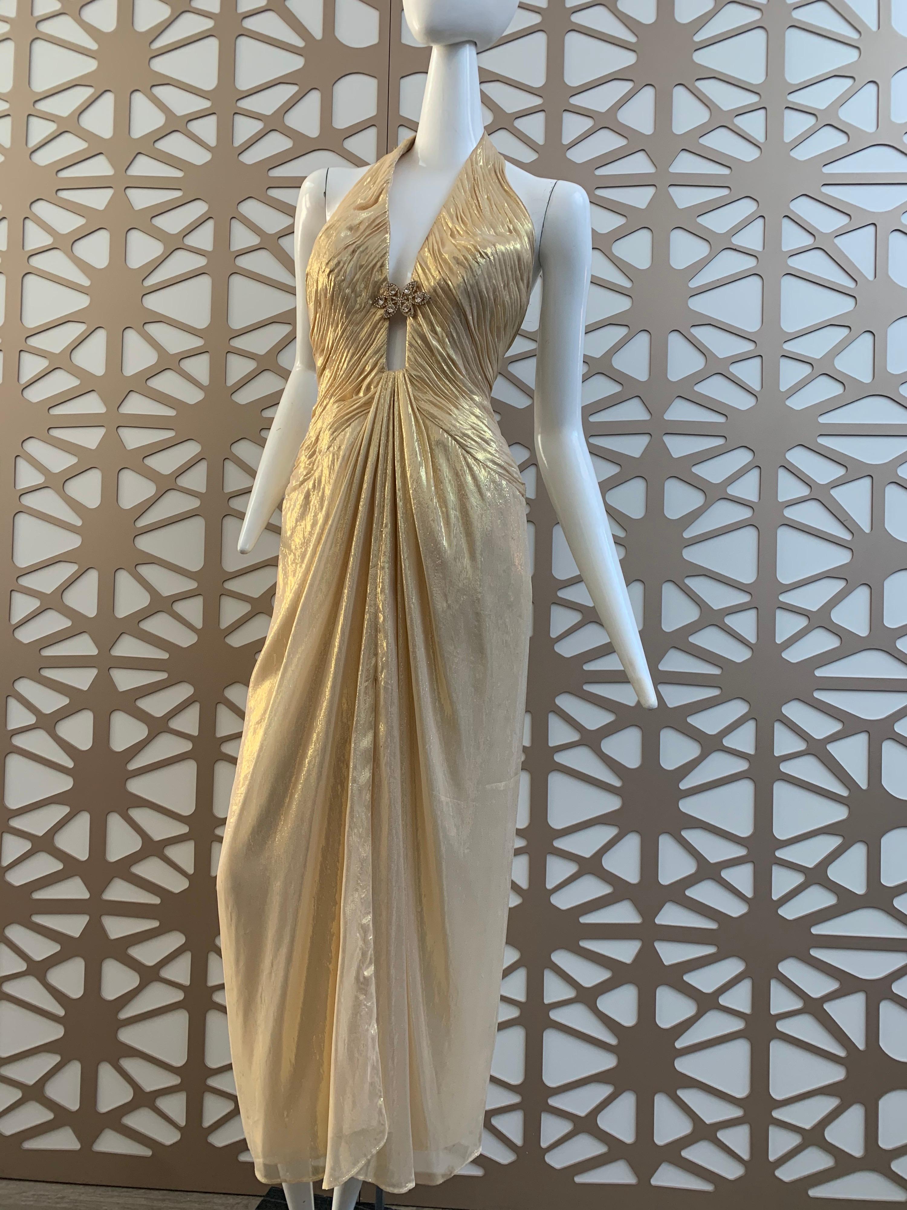 A glorious 1990s Michael Casey Couture gold silk lame goddess gown with structured and boned bodice, halter closure and a plunging neckline held in place by a beaded medallion.  Front center fan pleating flows from deep neckline. High center slit.