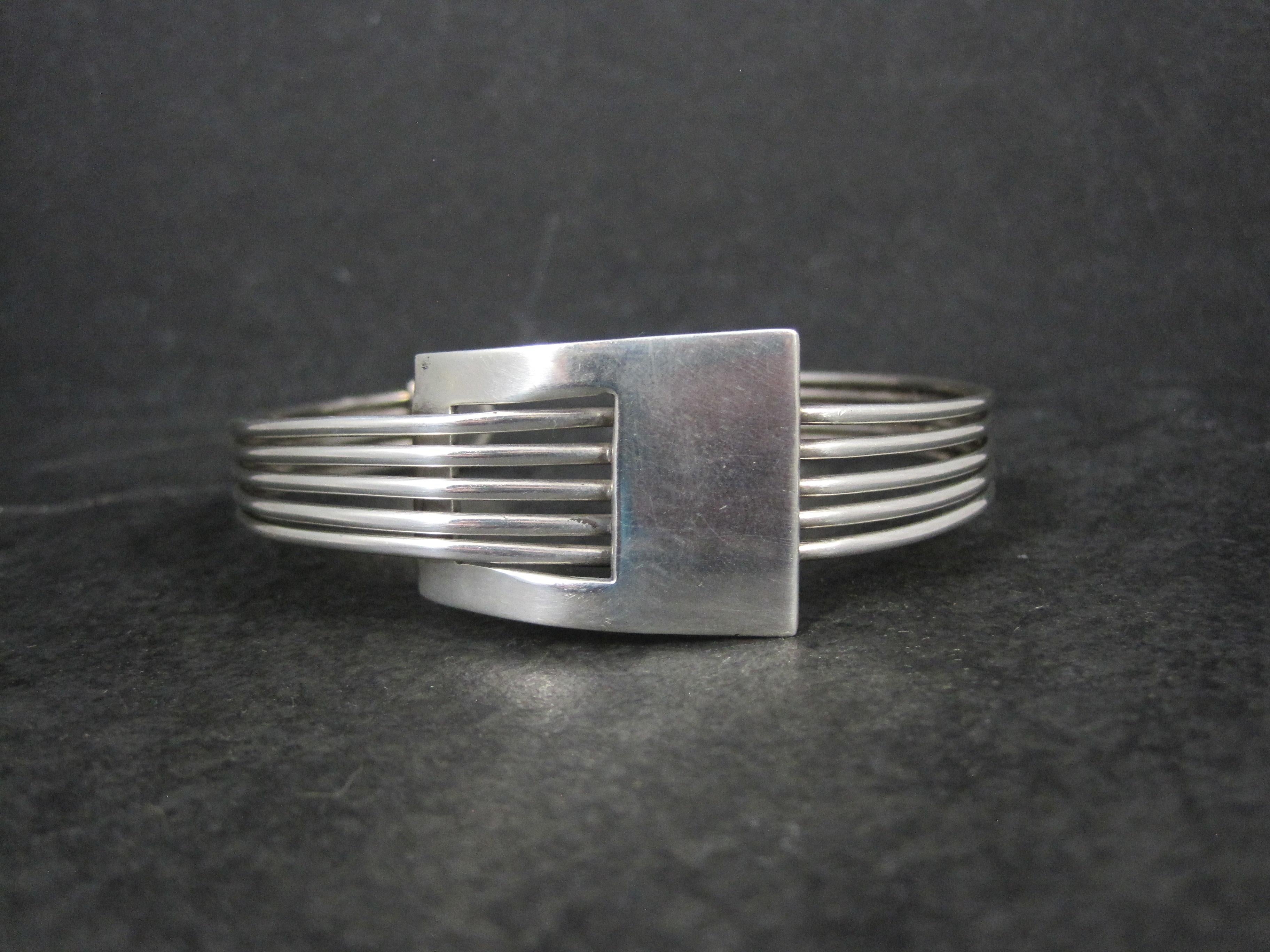 This gorgeous, mod style cuff bracelet is sterling silver.

The face of this cuff measures 7/8 of an inch at its widest point and tapers down to 3/8 of an inch.
It has an inner circumference of 7 inches, including the 1 inch gap.
Weight: 26.8