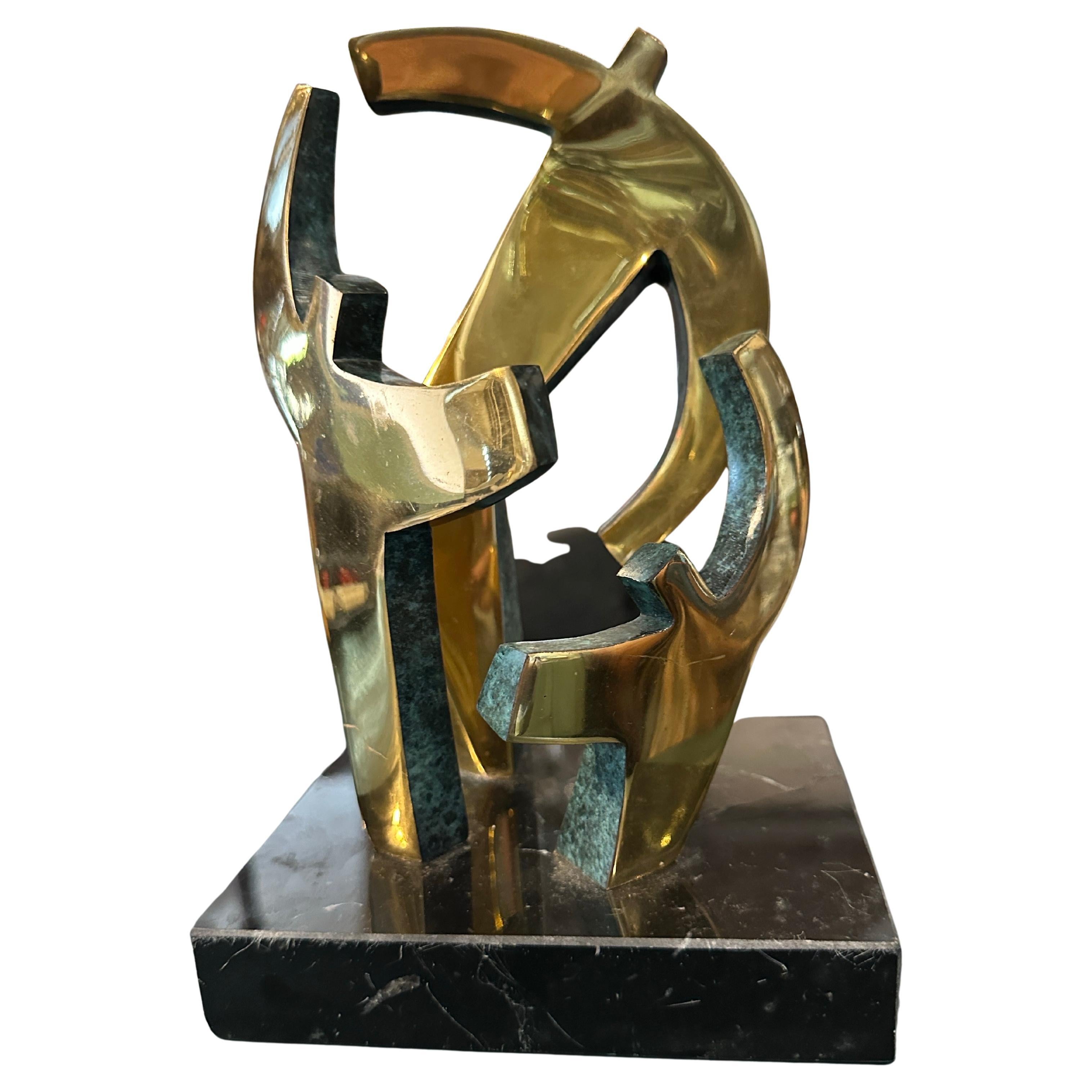 Esta impresionante escultura vintage, creada en la década de 1990, es un bello ejemplo de expresión abstracta. La pieza está fabricada en bronce dorado con una llamativa pátina verde en algunas de las superficies, que contrasta maravillosamente con