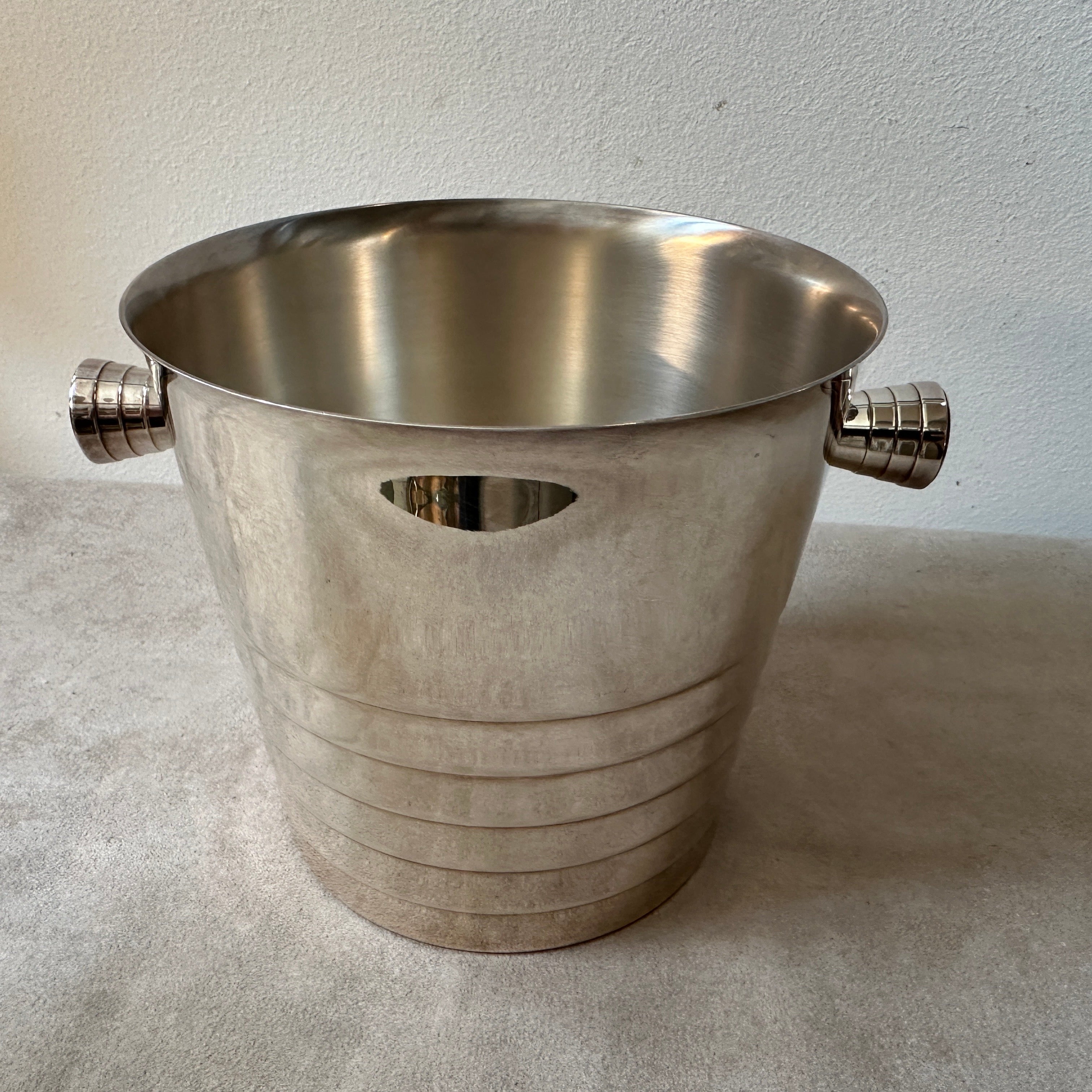 This French Ice Bucket by Christofle is a sleek and elegant piece of barware, reflecting the minimalist and contemporary design trends of the era. It has been crafted from high-quality silver-plated metal. Silver plating provides a luxurious finish