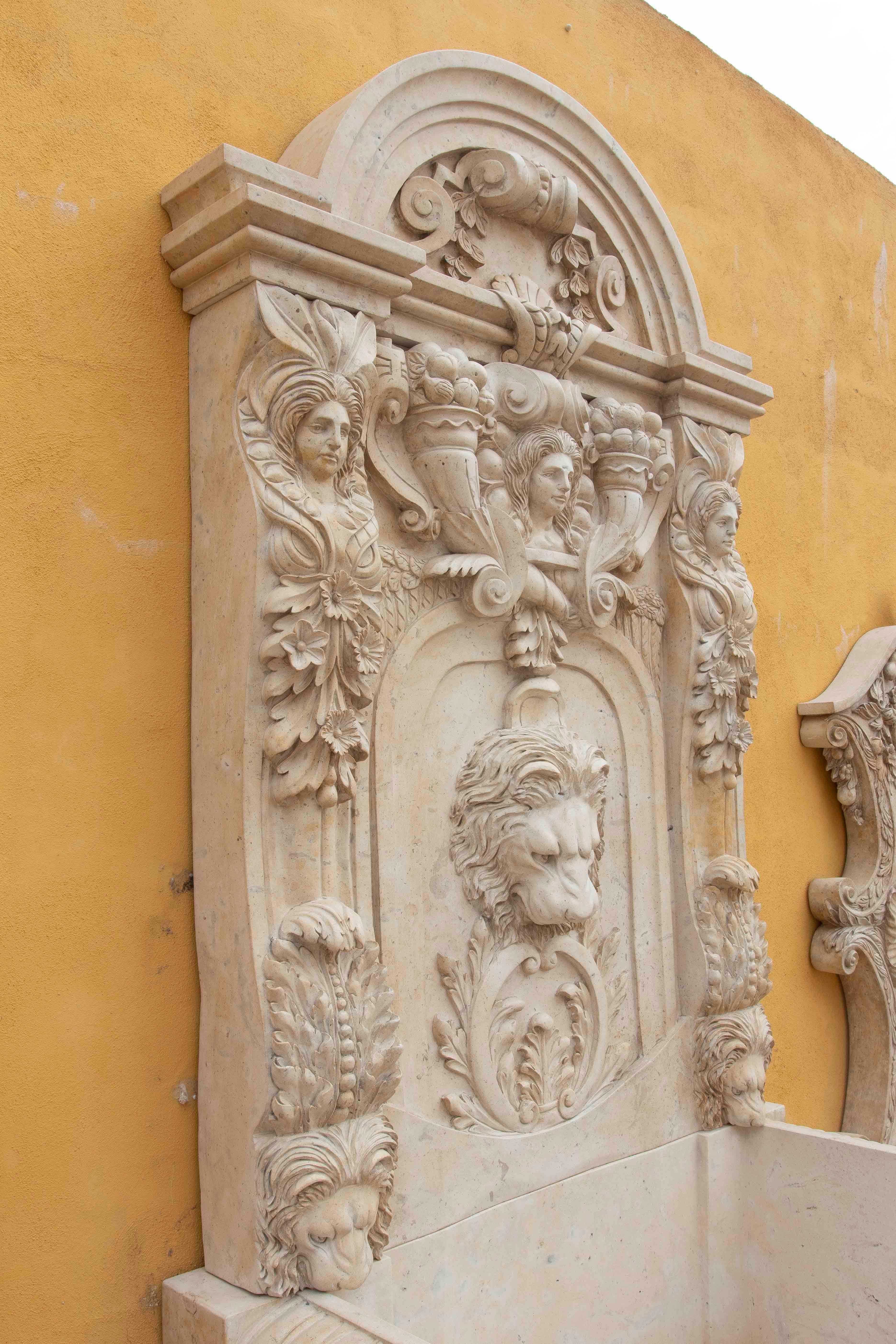 Impresionante fuente monumental de mármol tallado a mano, decorada con ricos detalles escultóricos de inspiración clásica. En el centro destaca una máscara de león en altorrelieve, símbolo de fuerza y protección, rodeada de motivos vegetales y