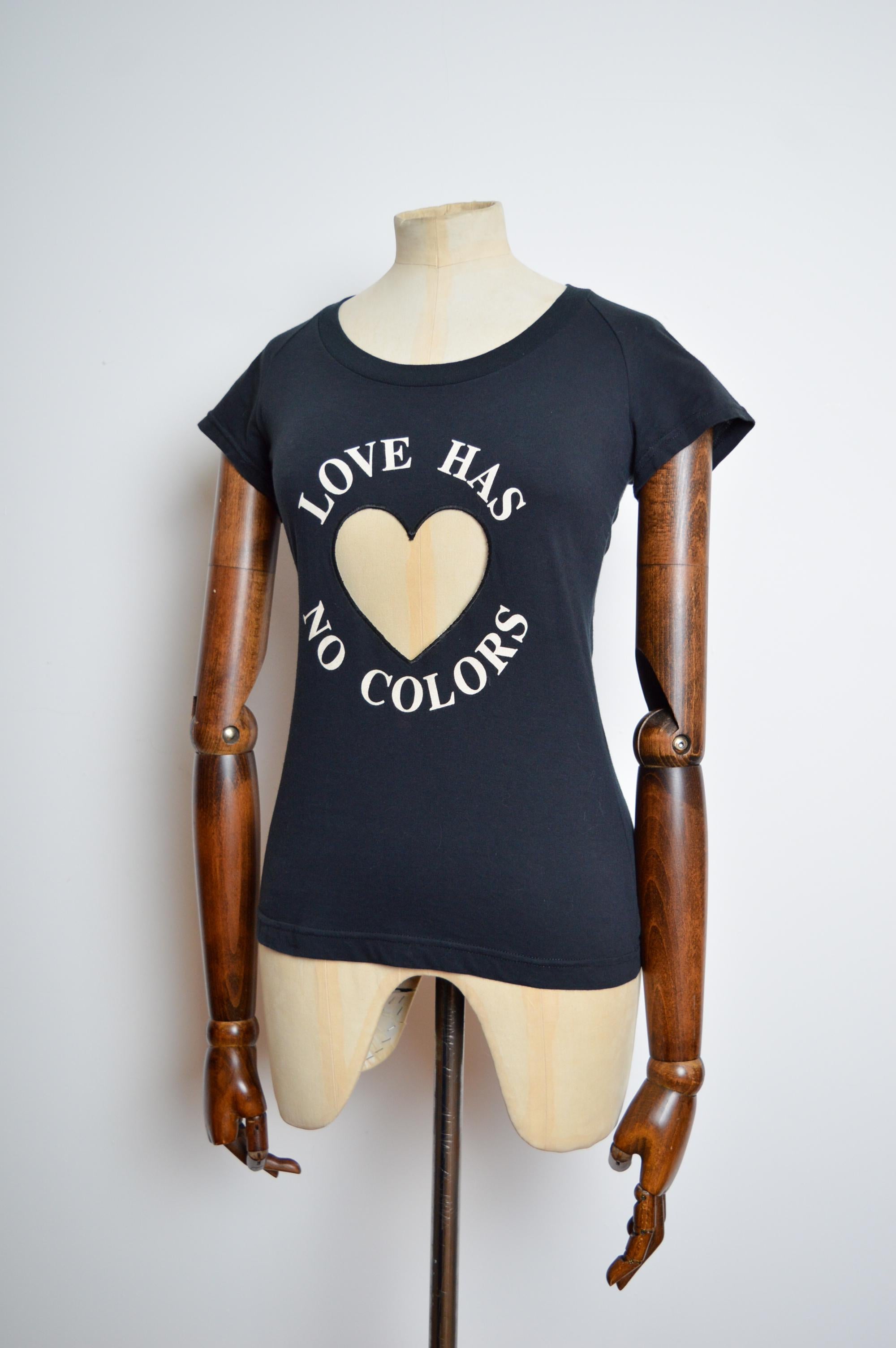 1990s Moschino Anti-Rascism ‘love has no colours’ fitted T-shirt 
MADE IN ITALY. 
Stretchy black cotton with cream print and transparent heart shaped pvc panel.
Pit to Pit; 17-18”
Nape to Hem; 24”
Waist; 28-30”
Size; Recommended size U.K. medium