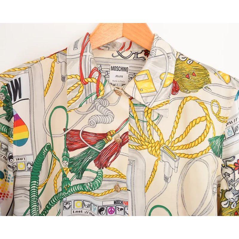Vintage 1990s Moschino 'Apple Mac' patterned parody shirt, in white satin feel fabric. 

Features:
Central line button fasten
Long sleeves
Ladies fit
MADE IN ITALY

100% Polyester

Sizing in inches:
Pit to Pit: 19''
Pit to Cuff: 18''
Nape to Hem: