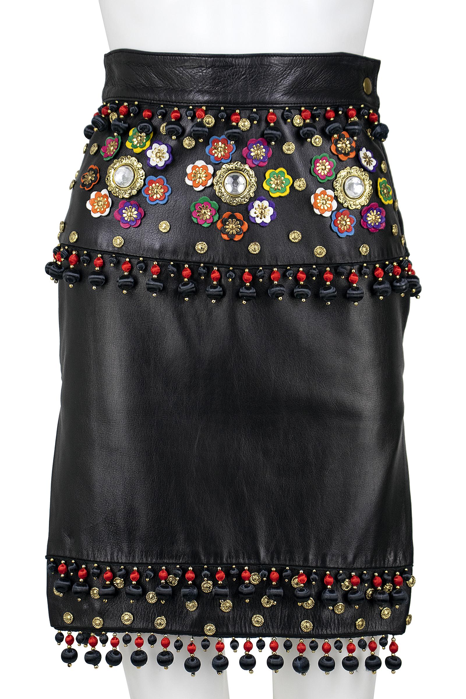 Moschino skirt 
Black leather 
Red and black beaded tassels 
Gold studs 
Colorful leather and gold flower applique 
Side zipper and snap 
Fully lined