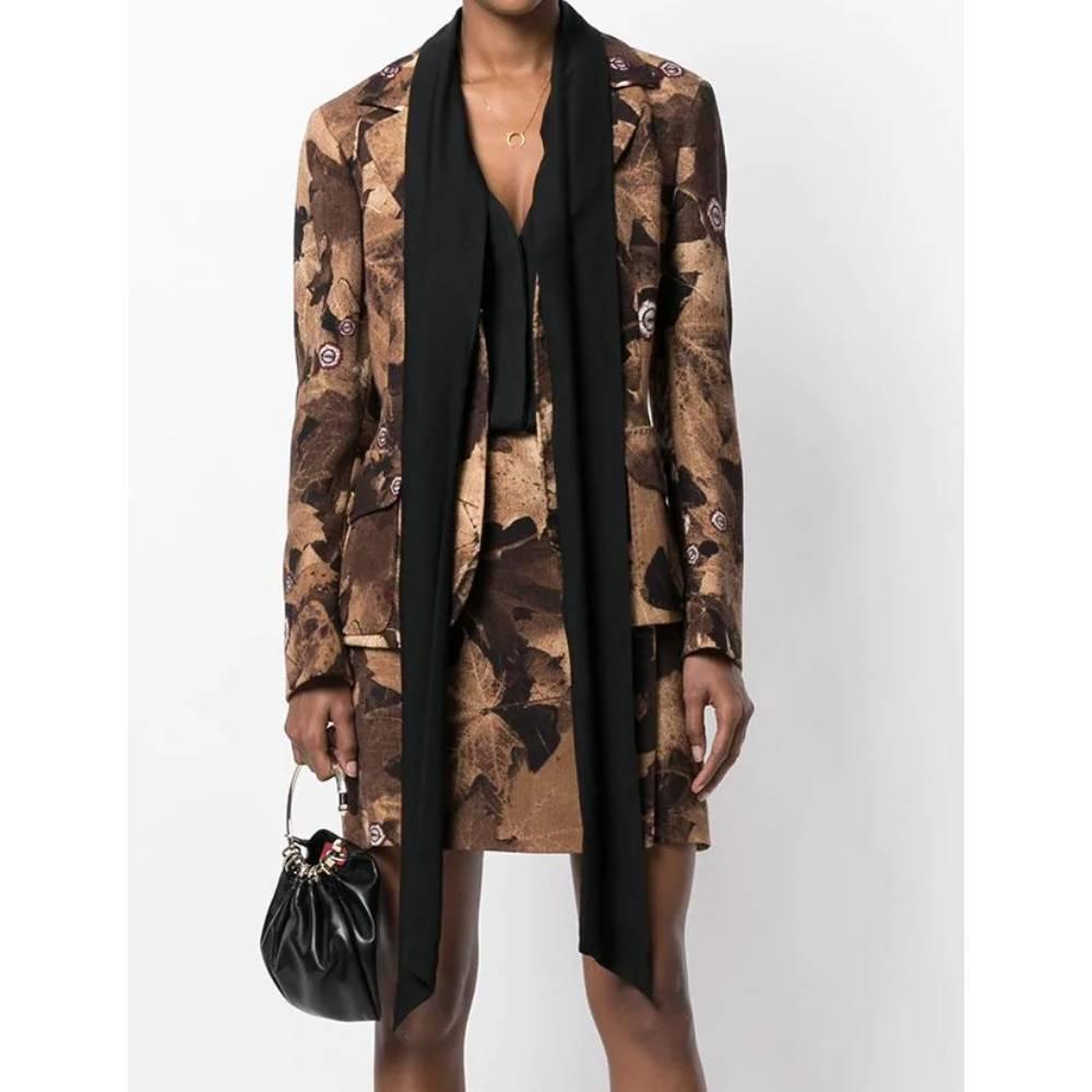 Moschino brown floral pattern wool suit. Classic lapel collar jacket, front button closure, long sleeves and pockets with flap and button; skirt trapeze above the knee, and high waist.

Years: 90s

Made in Italy

Size: 46 IT

Linear
