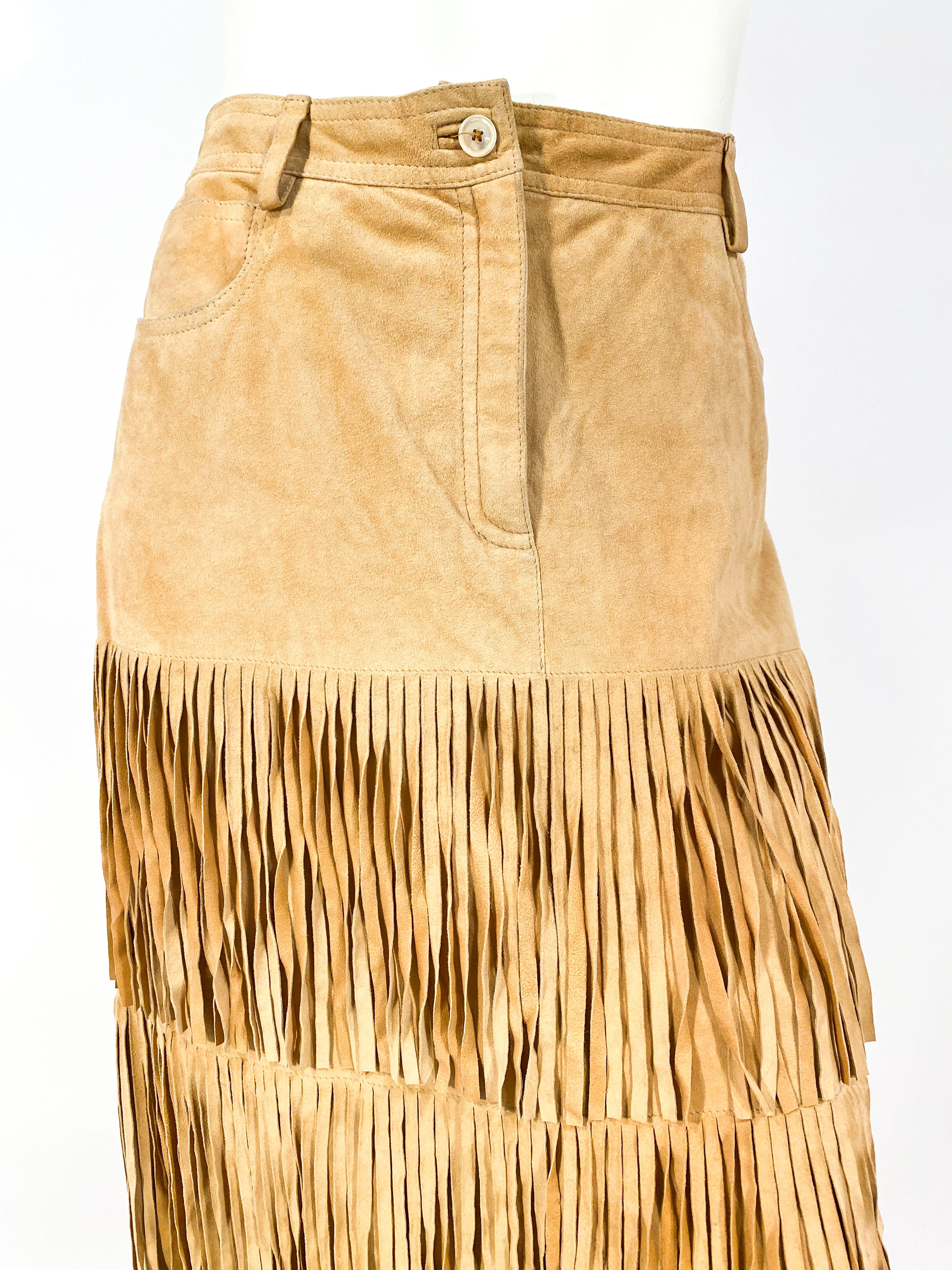 1990's' Moschino suede skirt featuring three long tiers of fringe that drop bellow the knee. The lining in the interior is to the knee and there is a back kick pleat. There are several front and back pockets and has attached belt loops for a belt. 