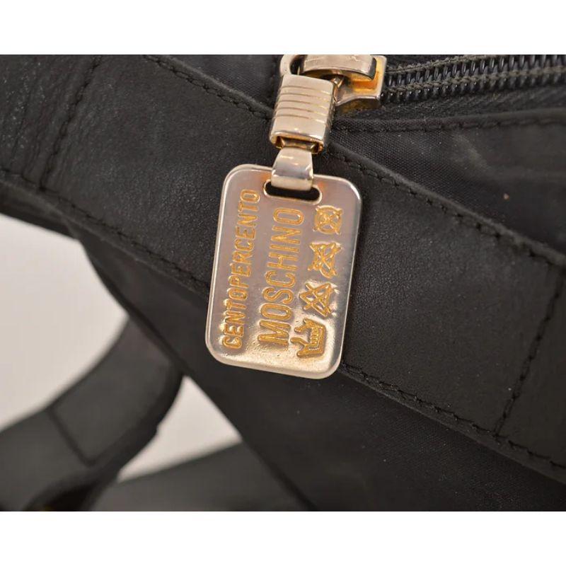 Sac à main / sac à dos en nylon noir Moschino des années 1990, avec l'emblématique et grand lettrage 'MOSCHINO' et des ferrures en métal doré.

Une pièce vintage iconique !

FABRIQUÉ EN ITALIE

Caractéristiques :
Grandes lettres 