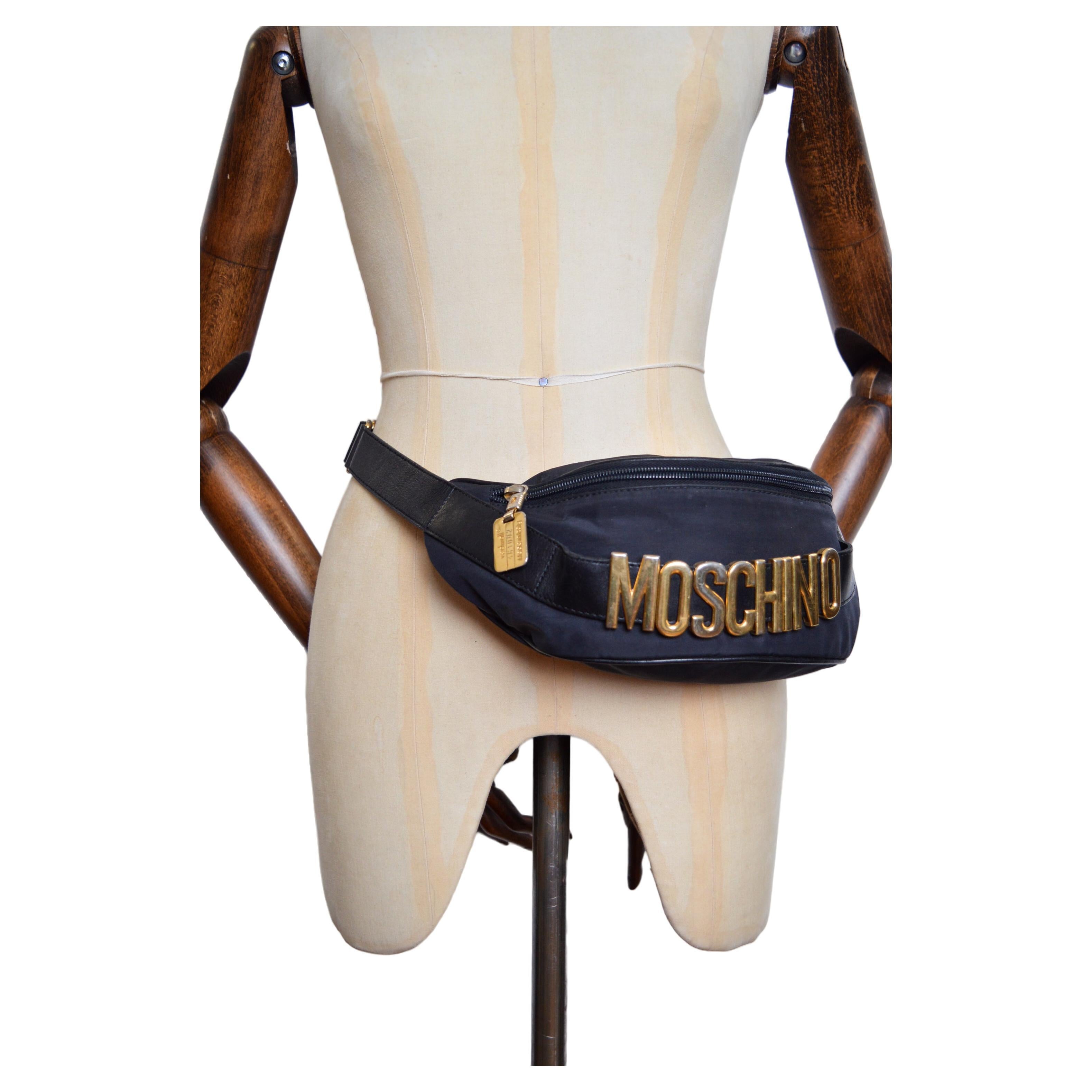 Vintage 1990's Moschino black nylon fanny pack / bum bag, with iconic & large 'MOSCHINO' lettering and gold tone metal hardware.  

An Iconic Vintage Piece !  

MADE IN ITALY  

Features: Large 'MOSCHINO' spellout letters, Single Zip fasten