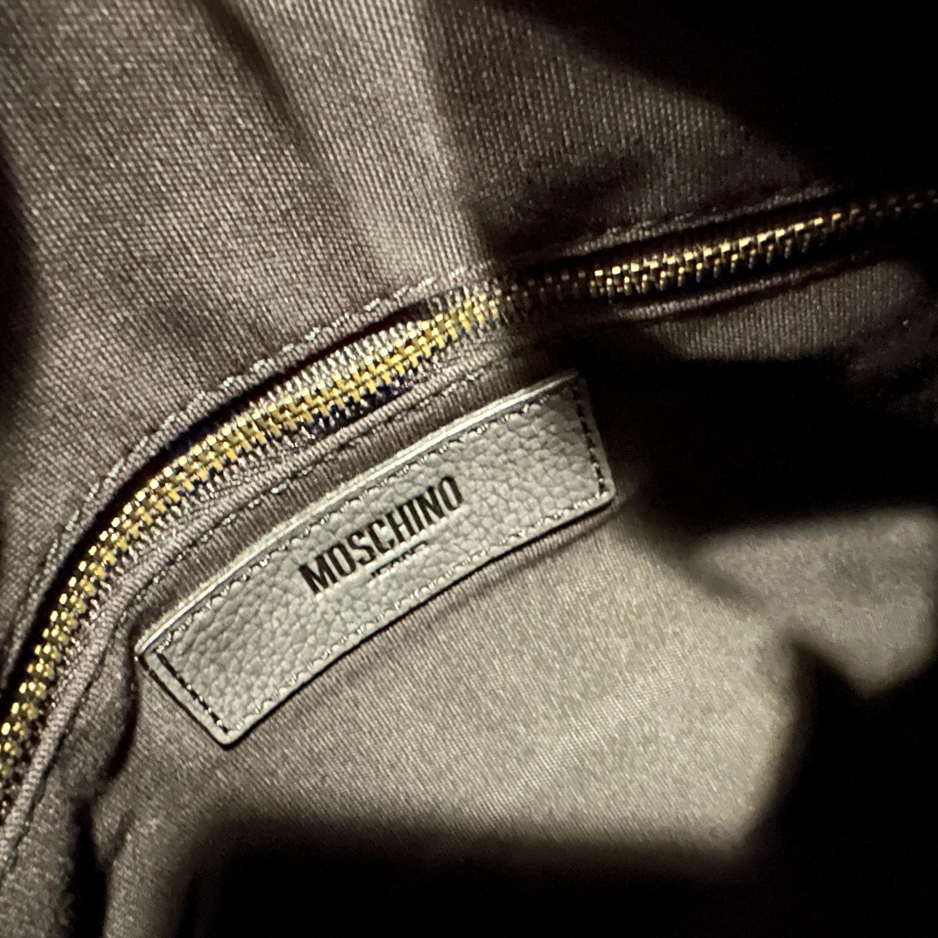 This rare and authentic Moschino Jeans top handle bag is a fantastic piece from the late 1990s, designed under the creative direction of Franco Moschino himself. This playful yet chic bag is crafted from a black felt-like fabric and features iconic