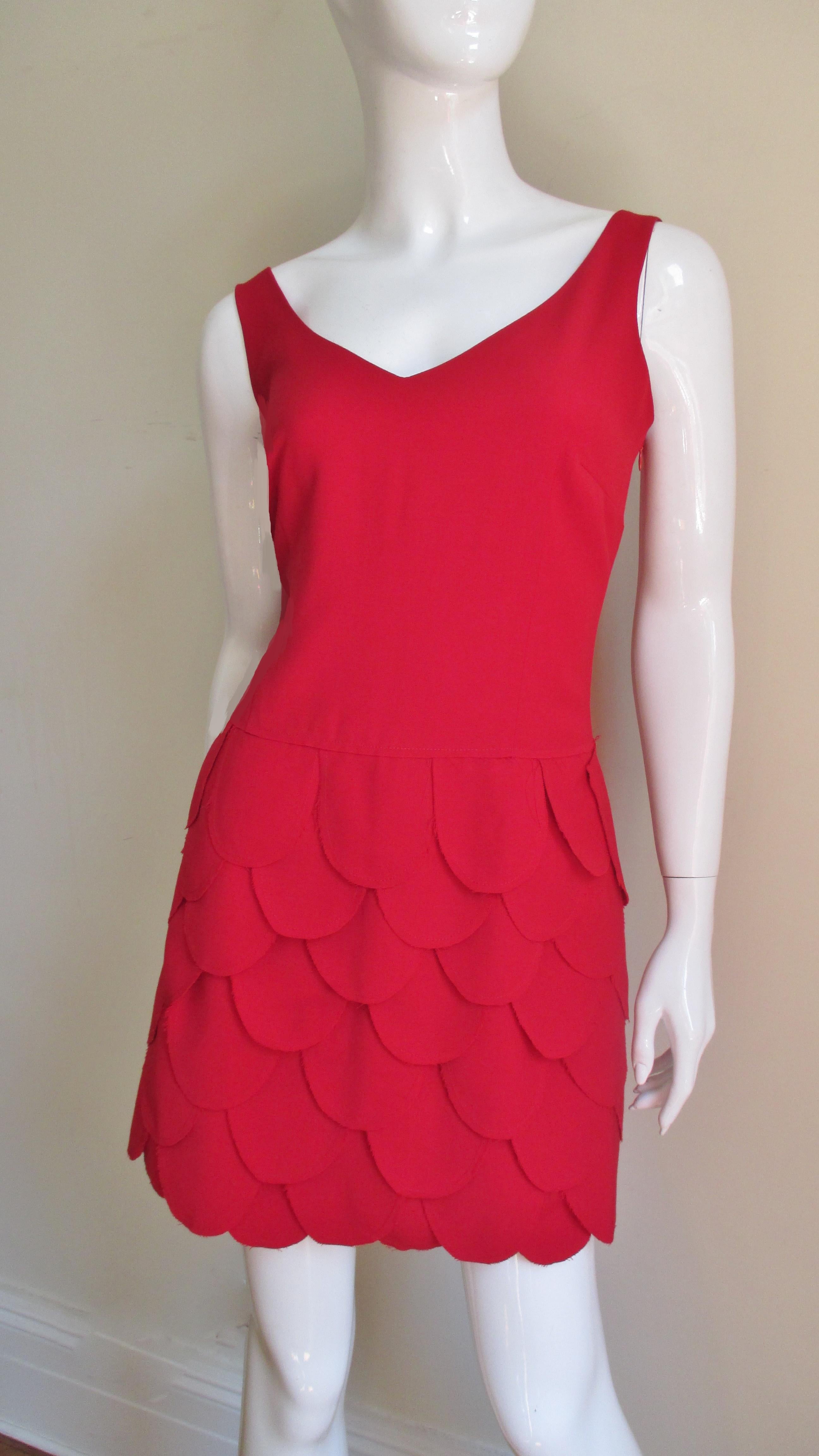 A fabulous light weight red wool dress from Moschino. It has a V neckline, scoop back and an A line skirt completely adorned in rows of overlapping individual fabric petals.  It is fully lined in matching red and has a side zipper.
New with tags