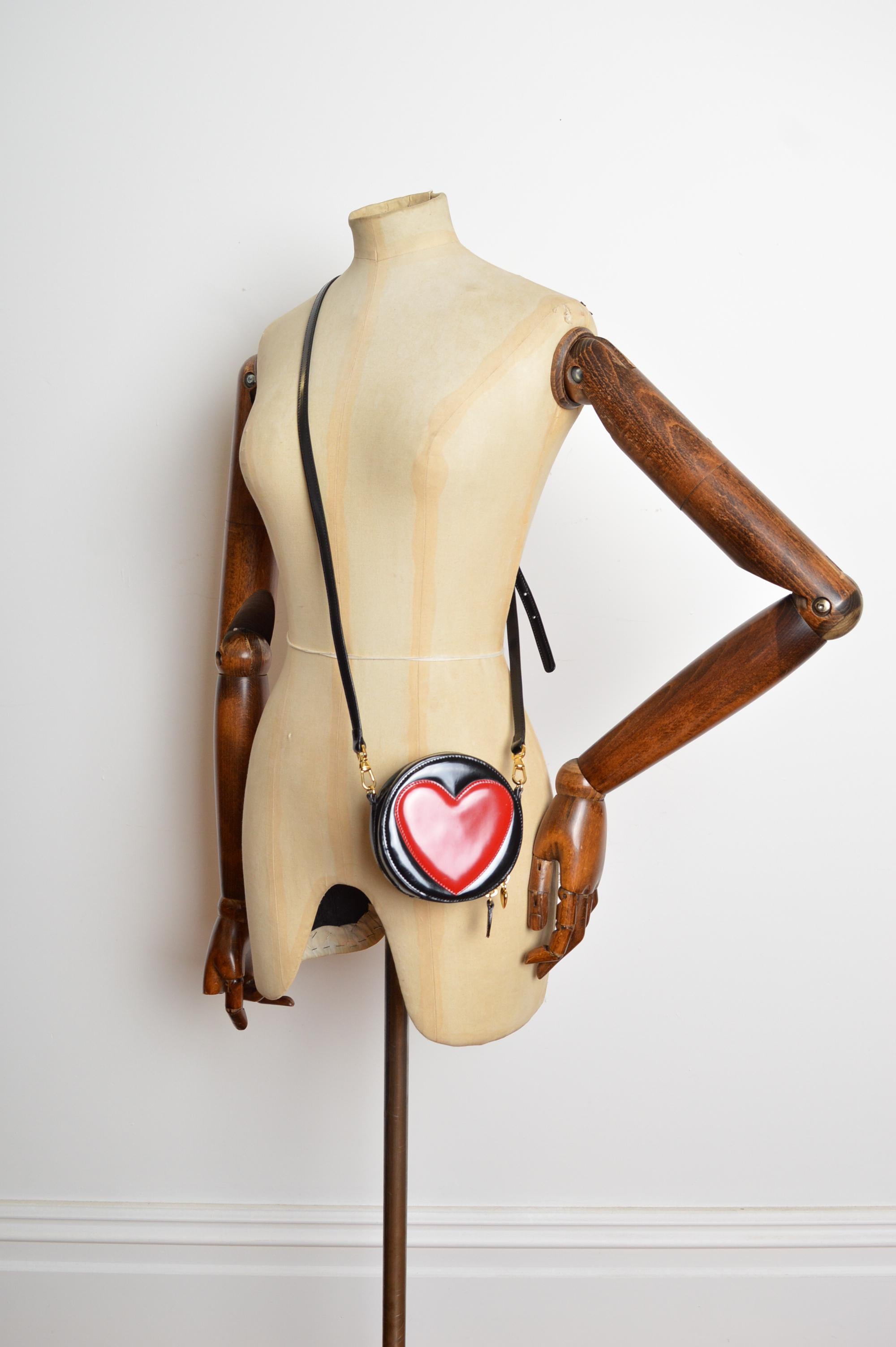 Mini sac en cuir Franco Moschino des années 1990. Il présente une forme circulaire, une double fermeture à glissière, un compartiment secret à l'intérieur, des accessoires en métal doré et une bandoulière détachable/ajustable. 
Les mesures sont