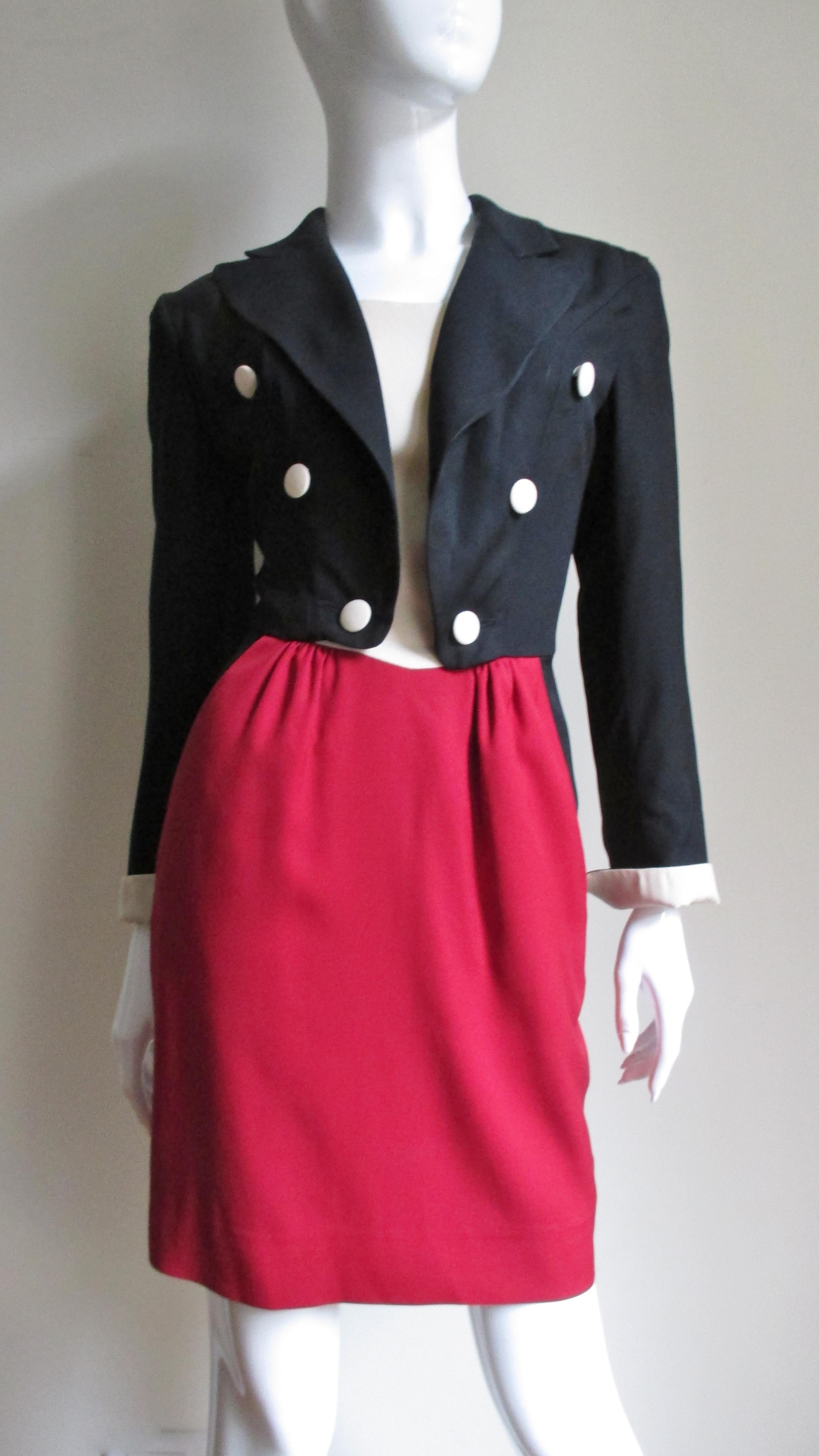 Une robe fantaisiste de Moschino en noir, rouge et blanc cassé. Le corsage se présente sous la forme d'une veste noire à double poitrine, avec des revers à pointe et des manches longues avec des poignets pliés assortis au haut blanc cassé qui