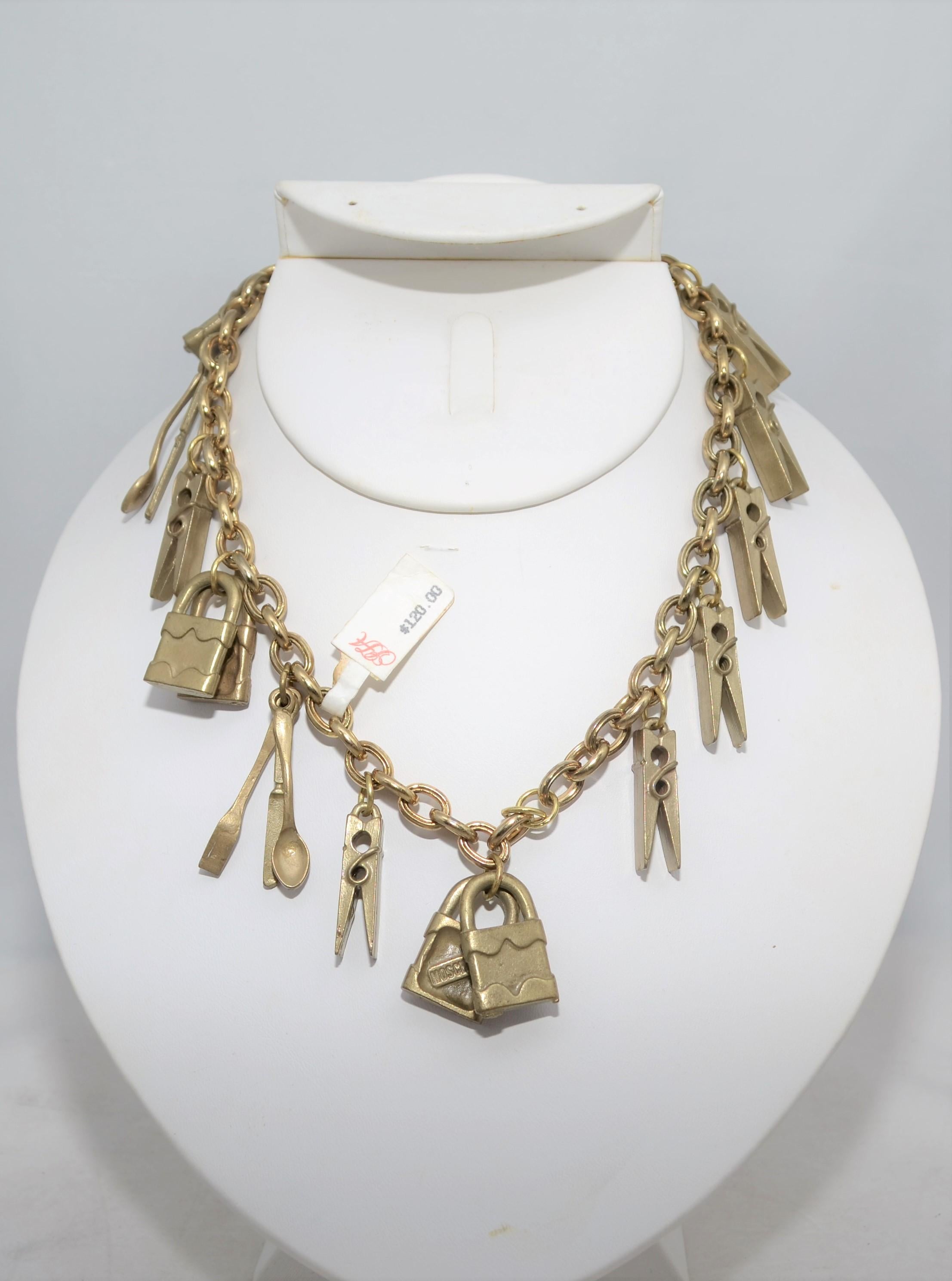 1990’s Moschino Vintage Chain Necklace with Padlock, Cutlery, and Clothespin Charms -- chain necklace is new with original tags and is featured in a brushed gold metal with fun assorted charms and a spring clasp closure. Chain length 15 inches.