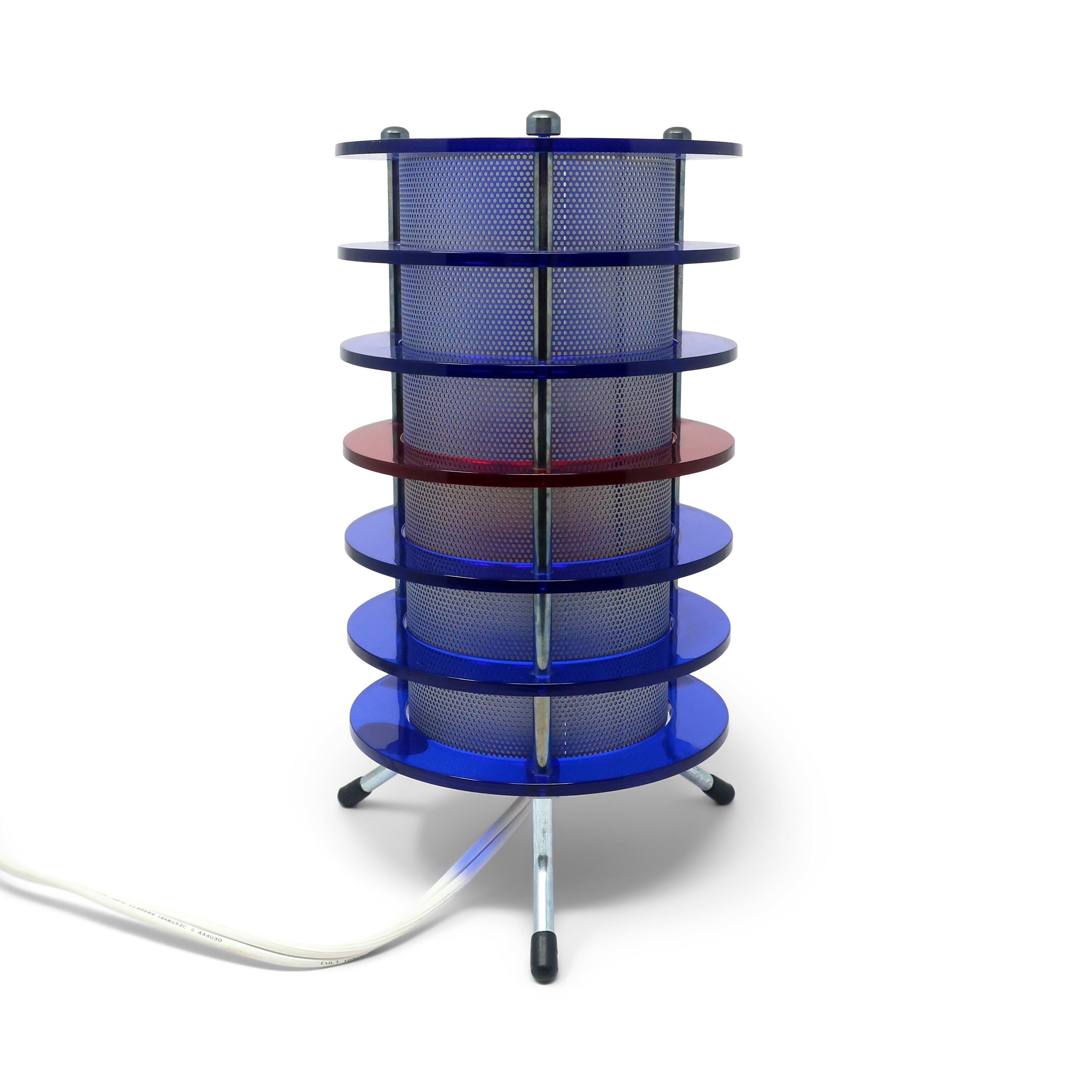 Eine fantastische zylindrische Tischlampe mit blauen und roten Lucit-Ringen, einem Netz im Inneren und einem verchromten Gestell, das die 1990er Jahre perfekt widerspiegelt!  

In sehr gutem Vintage-Zustand mit alters- und gebrauchsbedingten