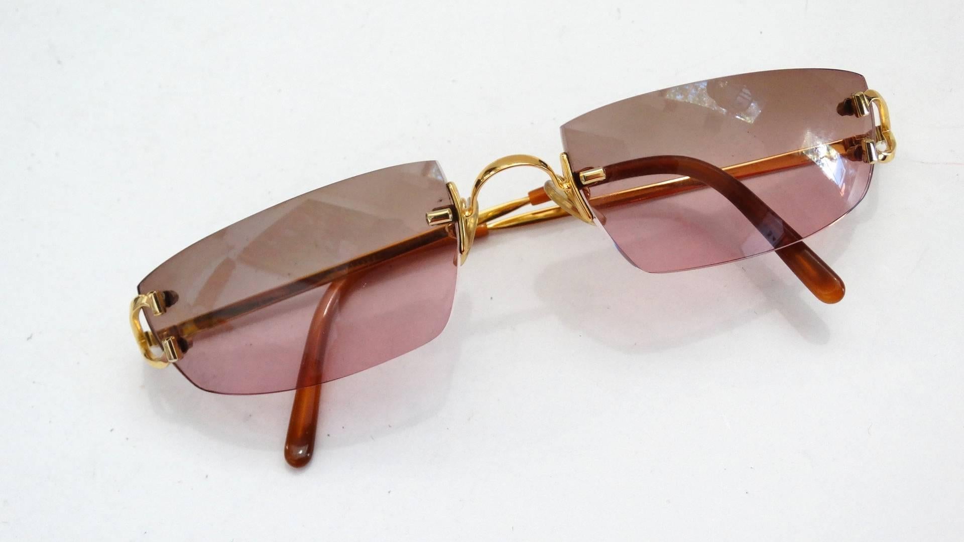 Cartier is always in style! These sunglasses are no exception, made with thick cut lenses in a pink ombre fade, contrasted by the gold wire frame. Rimless style with a unique shape, sharp and straight along the tops of the lens but sloped at the