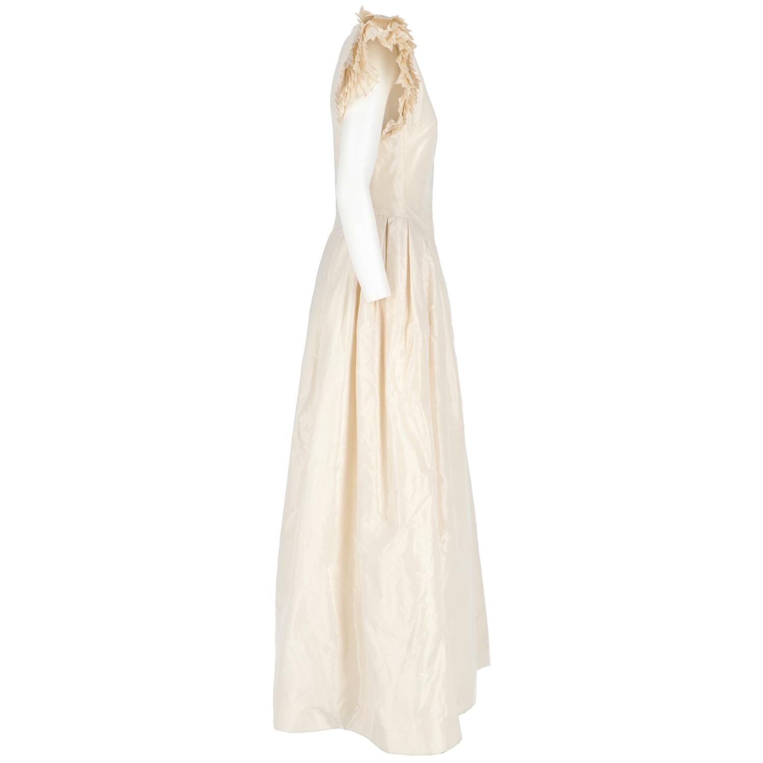 The romantic Nina Ricci Paris ivory silk long wedding dress features a long bell flared skirt with v-neck and pleated short-sleeves, shoulder paddings and back zip fastening.

Size: 44 IT
Made in France 
Linear measures

Height: 151 cm
Bust: 40