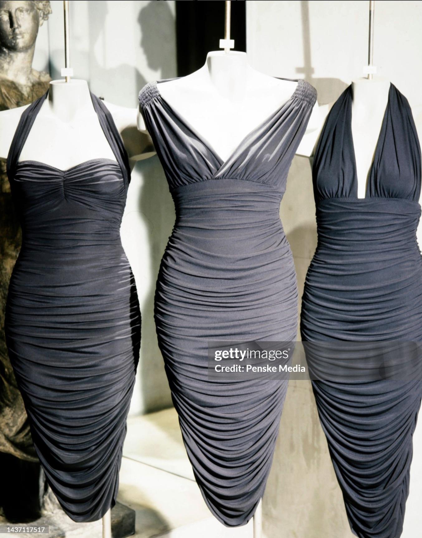Presenta uno splendido abito nero di Norma Kamali. Dalla collezione Autunno/Inverno 1995, questo abito a balze con spalle scoperte è ricoperto di ruche elastiche. Elegante, sexy e aderente, questo abito di Norma Kamali lungo fino alla caviglia con