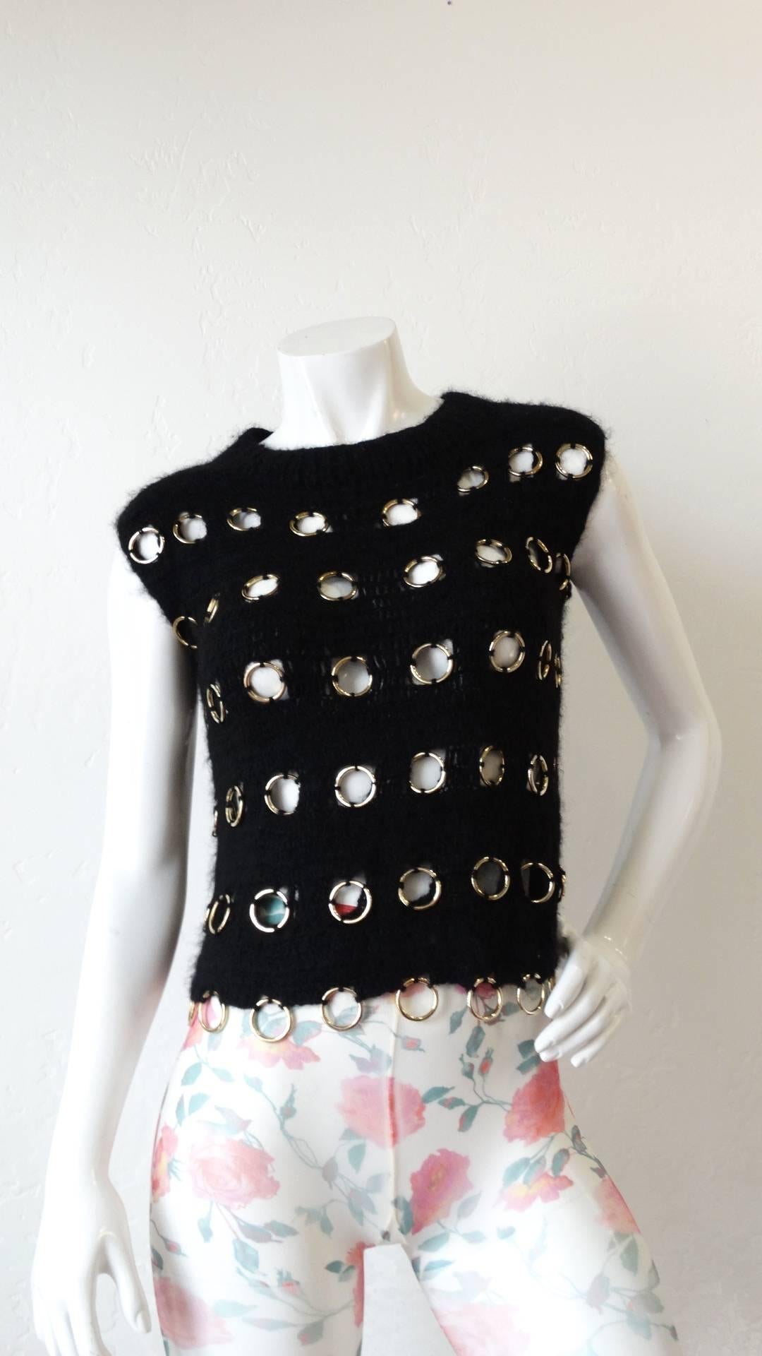 Rock a layered look with some edge with our amazing 1990s grommet knit top! Black crochet knit fabric with silver metal o-rings woven throughout.  Sleeveless fit with a high neckline. Wear with your favorite white button down underneath- or with