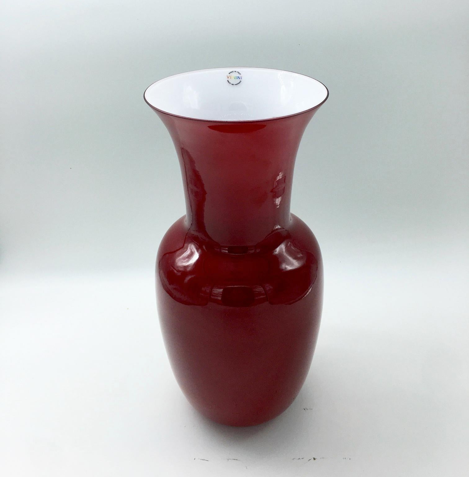 Venini glass vase with slim, oval shaped body and funnel shaped neck. Featured in red colored glass.