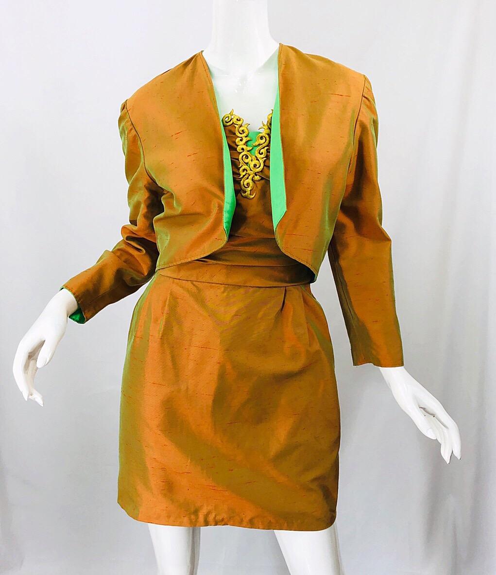Magnifique robe bustier métallique orange des années 1990 et veste boléro réversible assortie ! La mini-robe sans bretelles présente un corsage ajusté et une jupe souple. Broderie dorée le long du buste avec une touche de vert au centre du buste