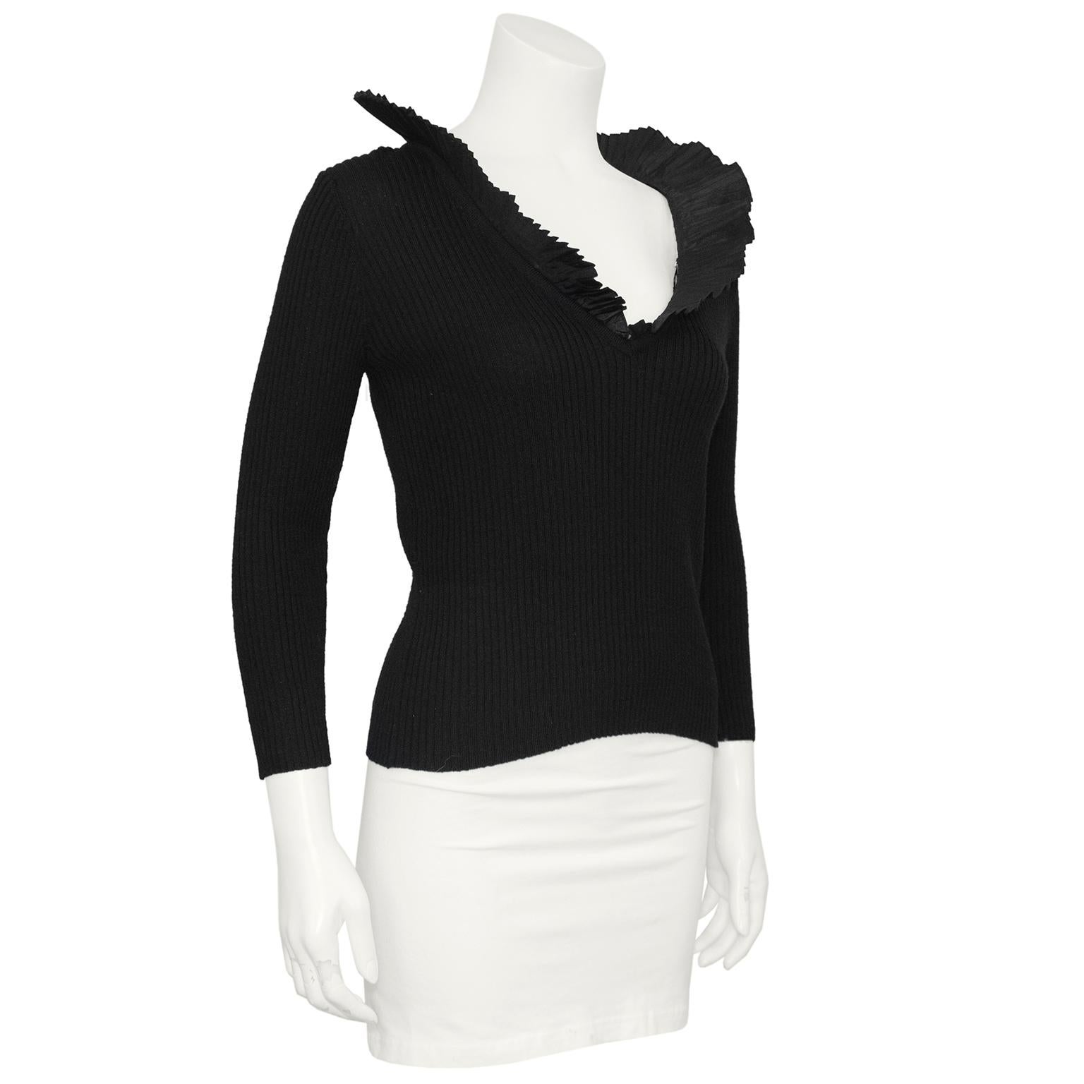 Classic, with a twist Oscar de la Renta sweater from the 1990s. Black and ribbed, this sweater is made from 100% fine Italian wool. The show stopping element of this piece is the dramatic micro pleated ruffle collar with a v neckline. Pair with