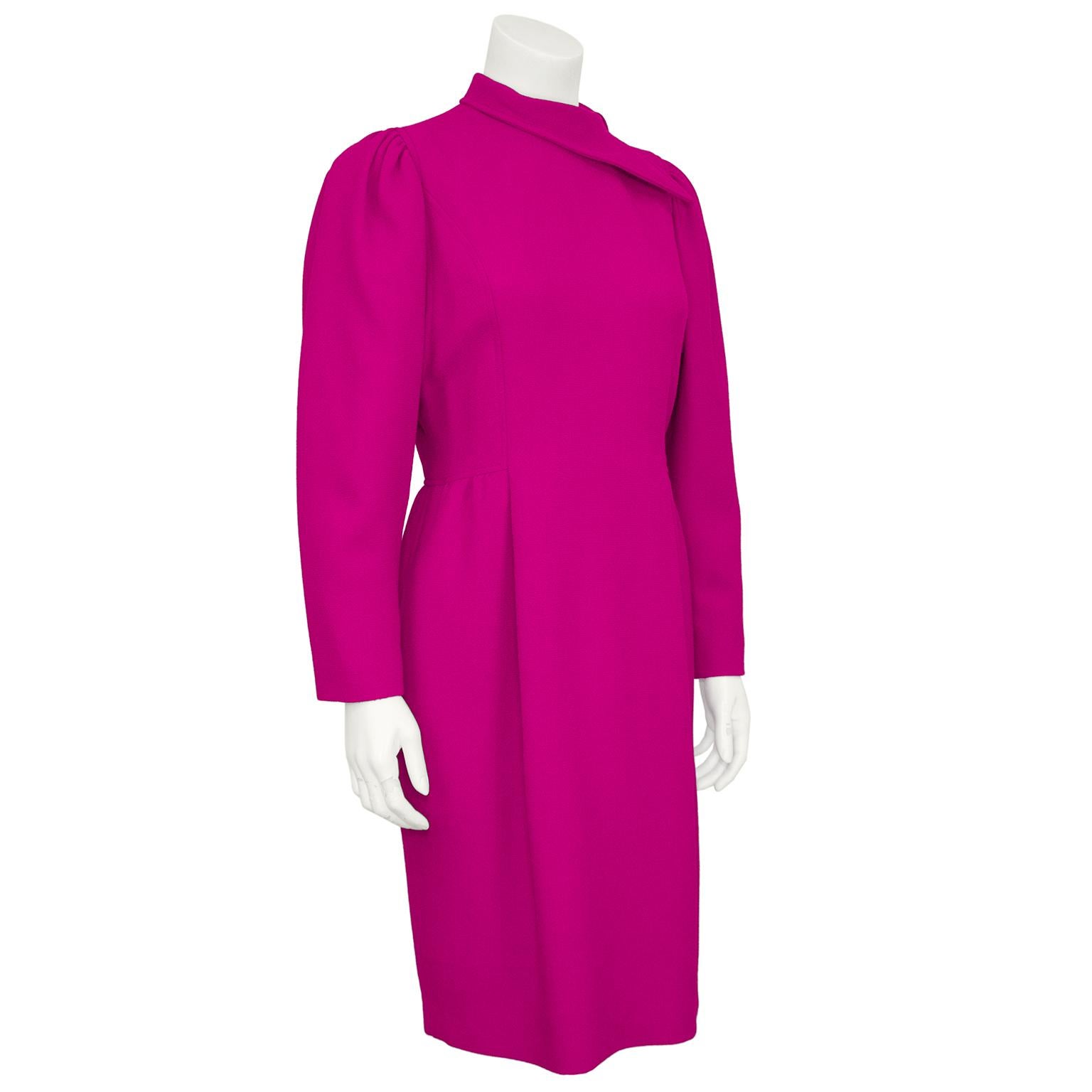 Beautiful Oscar de la Renta magenta wool cocktail dress from the 1990s. The dress features an interesting elongated sideways collar that gives the illusion of a scarf tied at the neck. Long gathered dolman sleeves and fitted through body with a