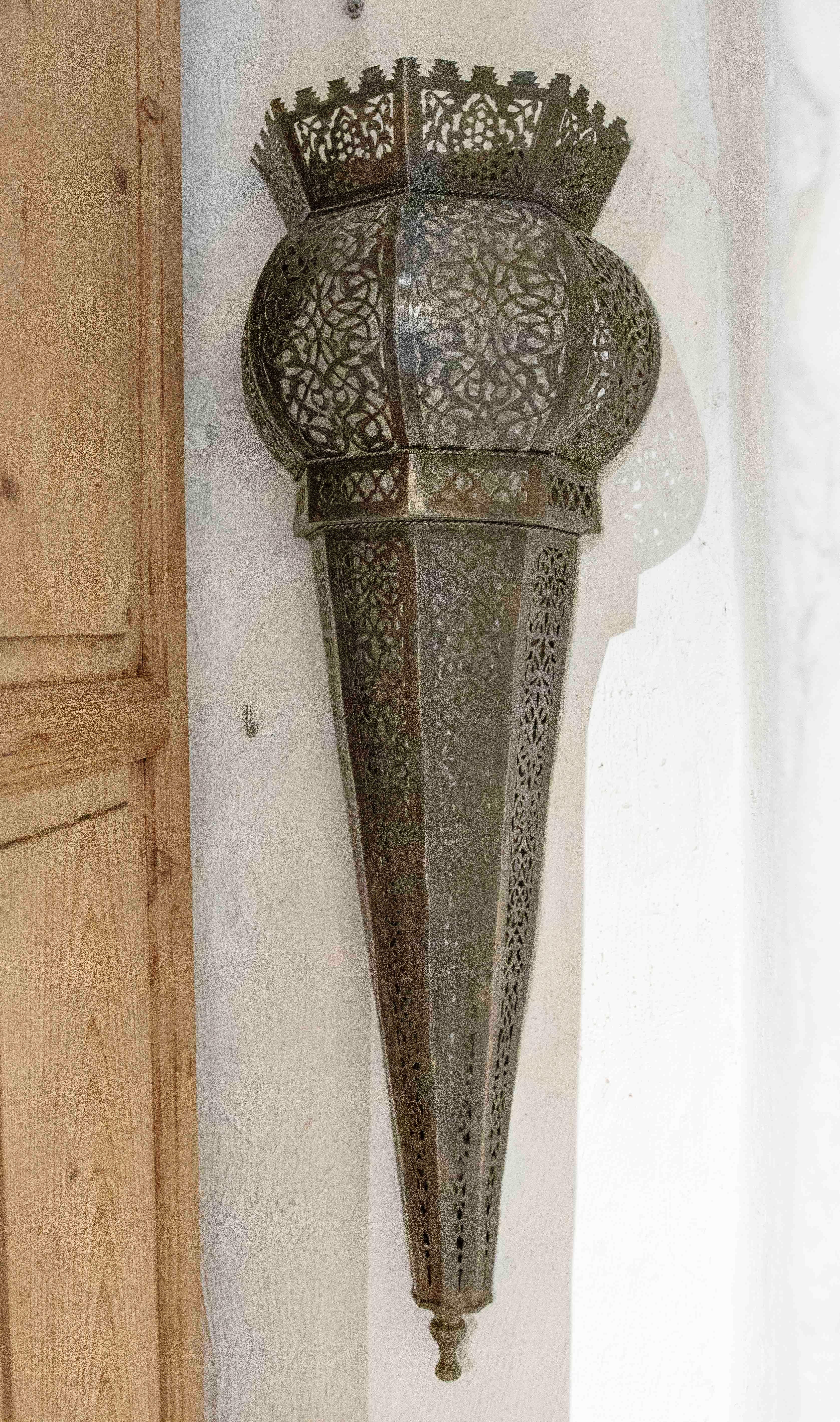A magnificent pair of Arabian style wall sconces, crafted in openwork metal with intricate geometric and floral designs. These pieces stand out for their craftsmanship, creating decorative lighting that casts beautiful patterns of shadows when lit,