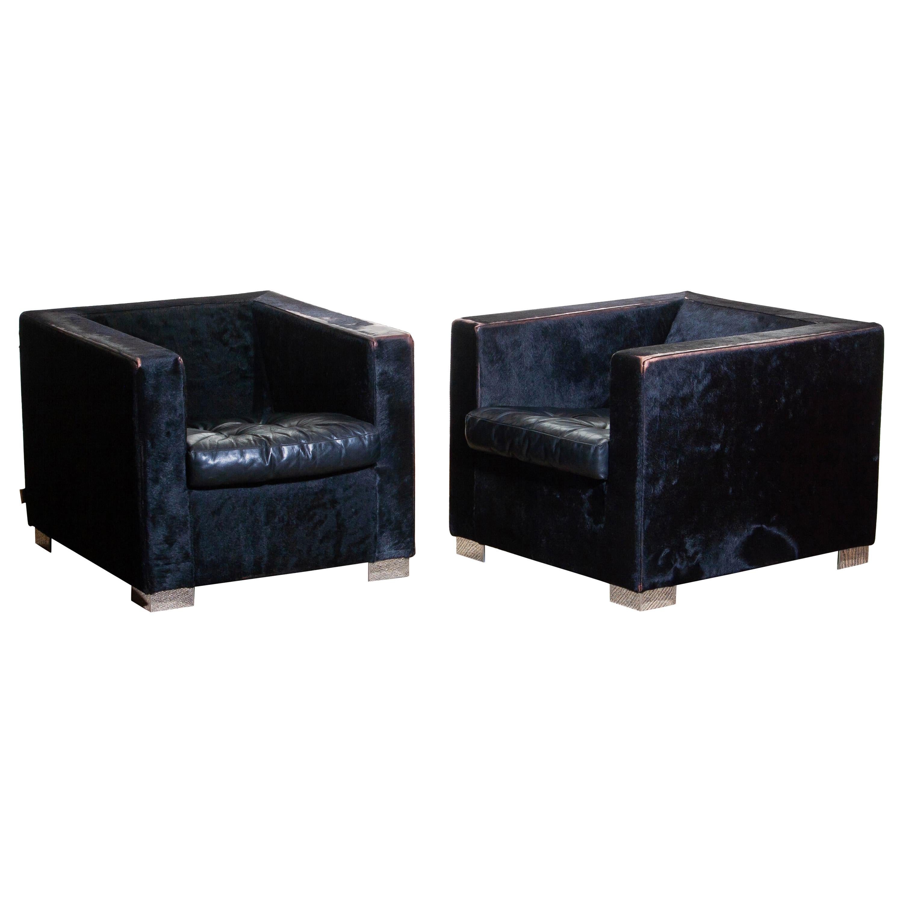 Contemporary set of two “Suitcase” armchairs designed by Rodolfo Dordoni for Minotti, 1990.
Upholstered with pony (black) and the padded seat cushion with (also black) leather.
All standing on squared chromed metal legs.

Note: One chair shows