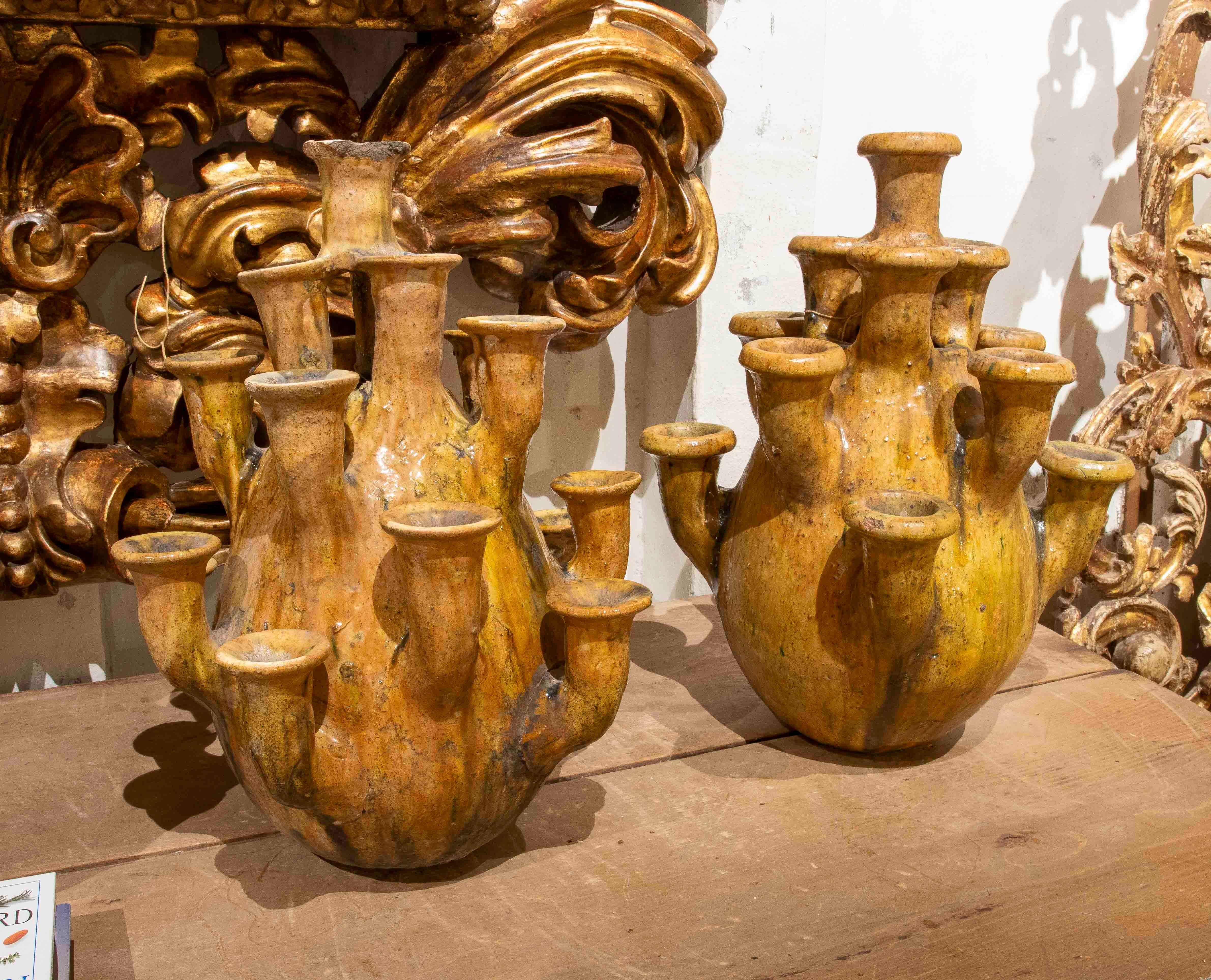 Paire de vases uniques en céramique émaillée dans des tons jaunes chauds, chacun doté de multiples becs qui lui confèrent un caractère sculptural et hautement décoratif. Leur forme organique et leur finition vieillie évoquent des pièces