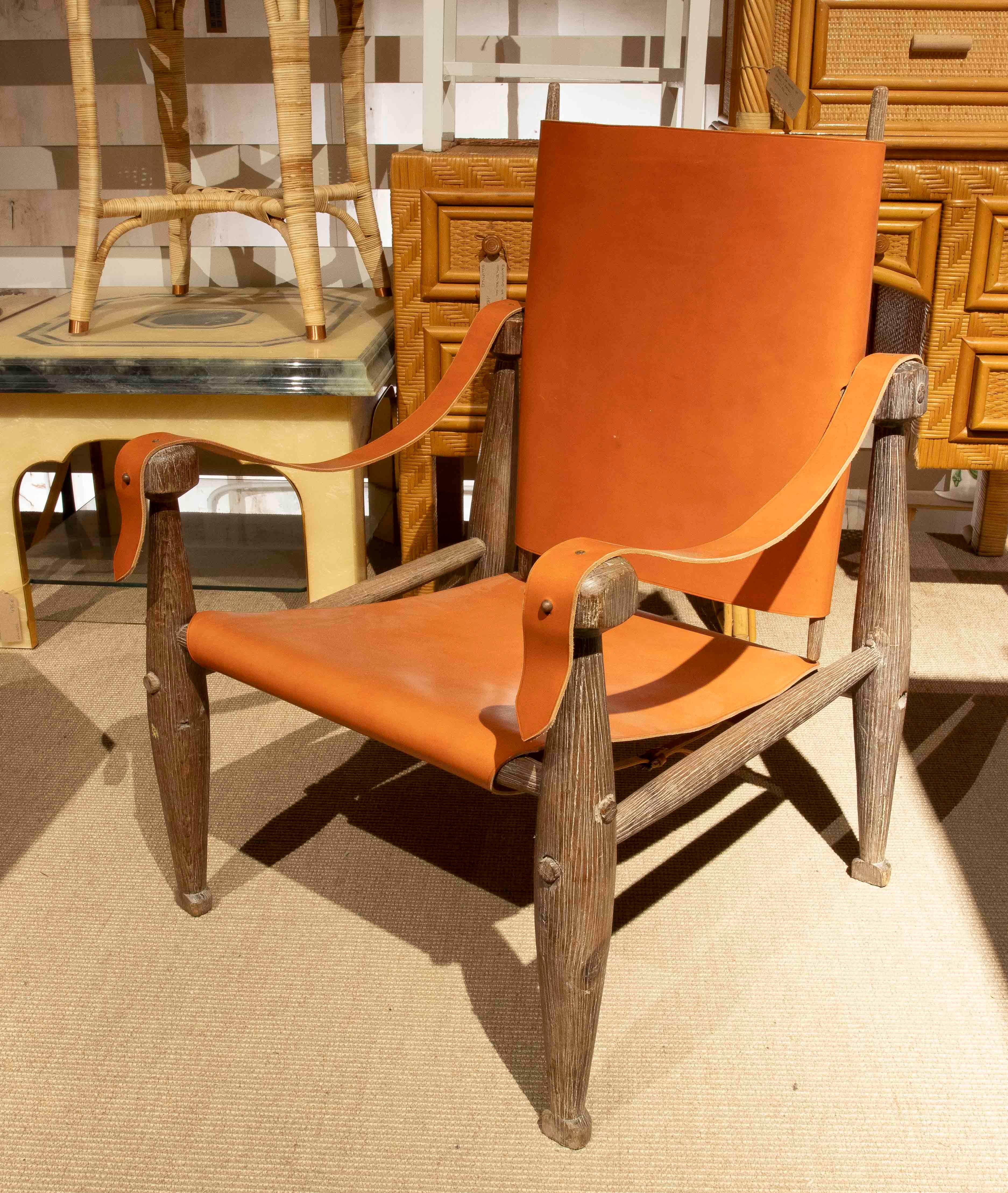 Un'elegante coppia di poltrone safari con struttura in legno massiccio e rivestimento in pelle naturale color cognac su seduta, schienale e braccioli. Il loro design funzionale e senza tempo riflette l'estetica scandinava di metà secolo, combinando