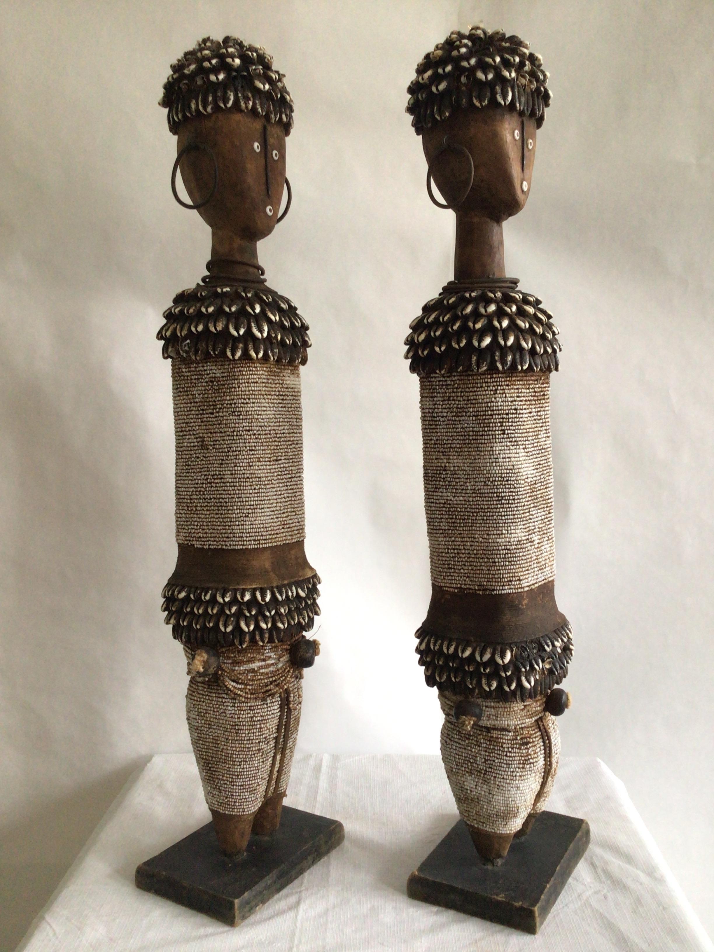 1990s Pair of Wood And Shells Beaded Namji Dolls
Made with wood, beads and cowrie shells
Metal Earings
Some cracks in the shells on top of the head 

